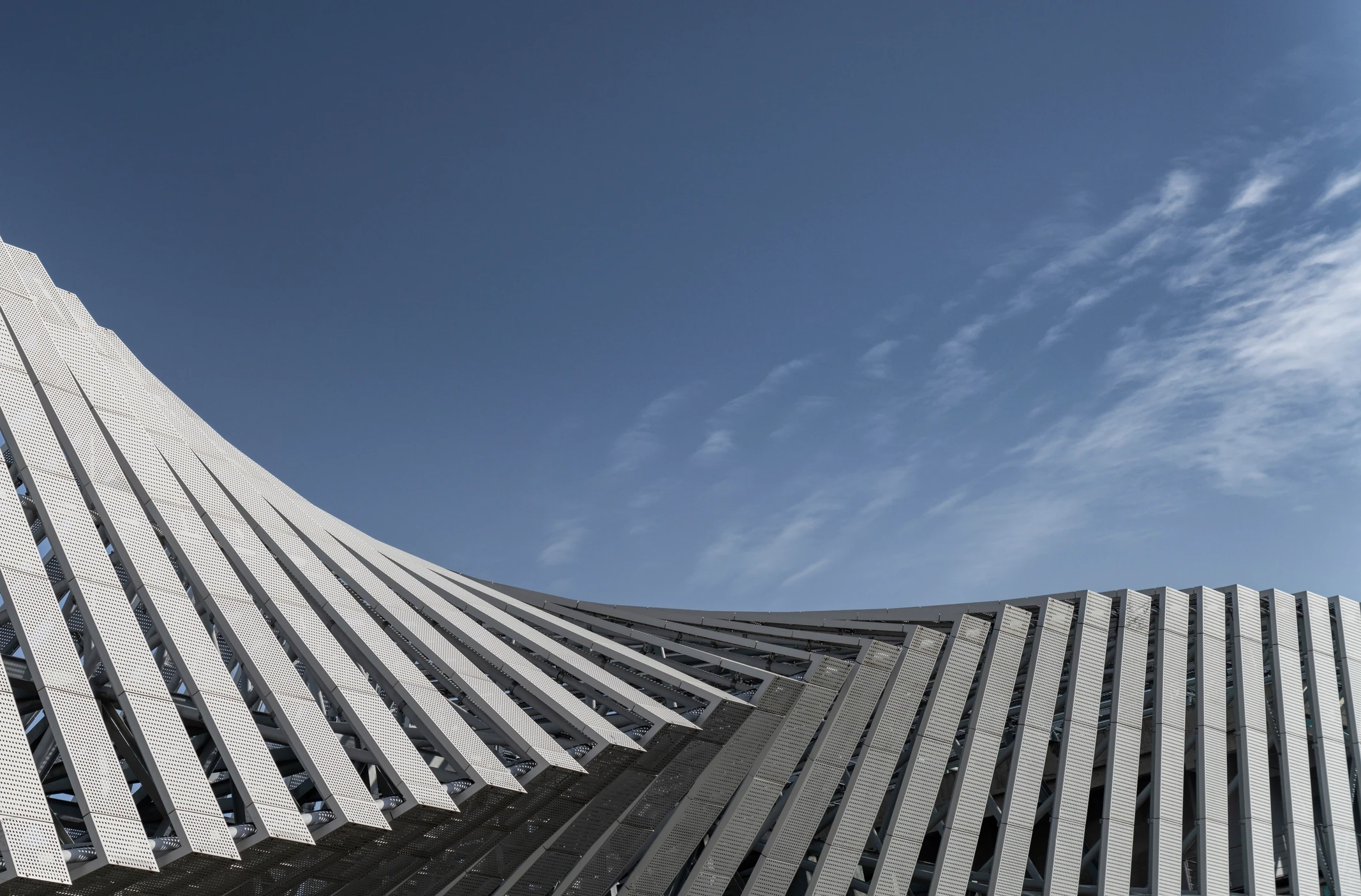 Geometric building set against blue sky with clouds