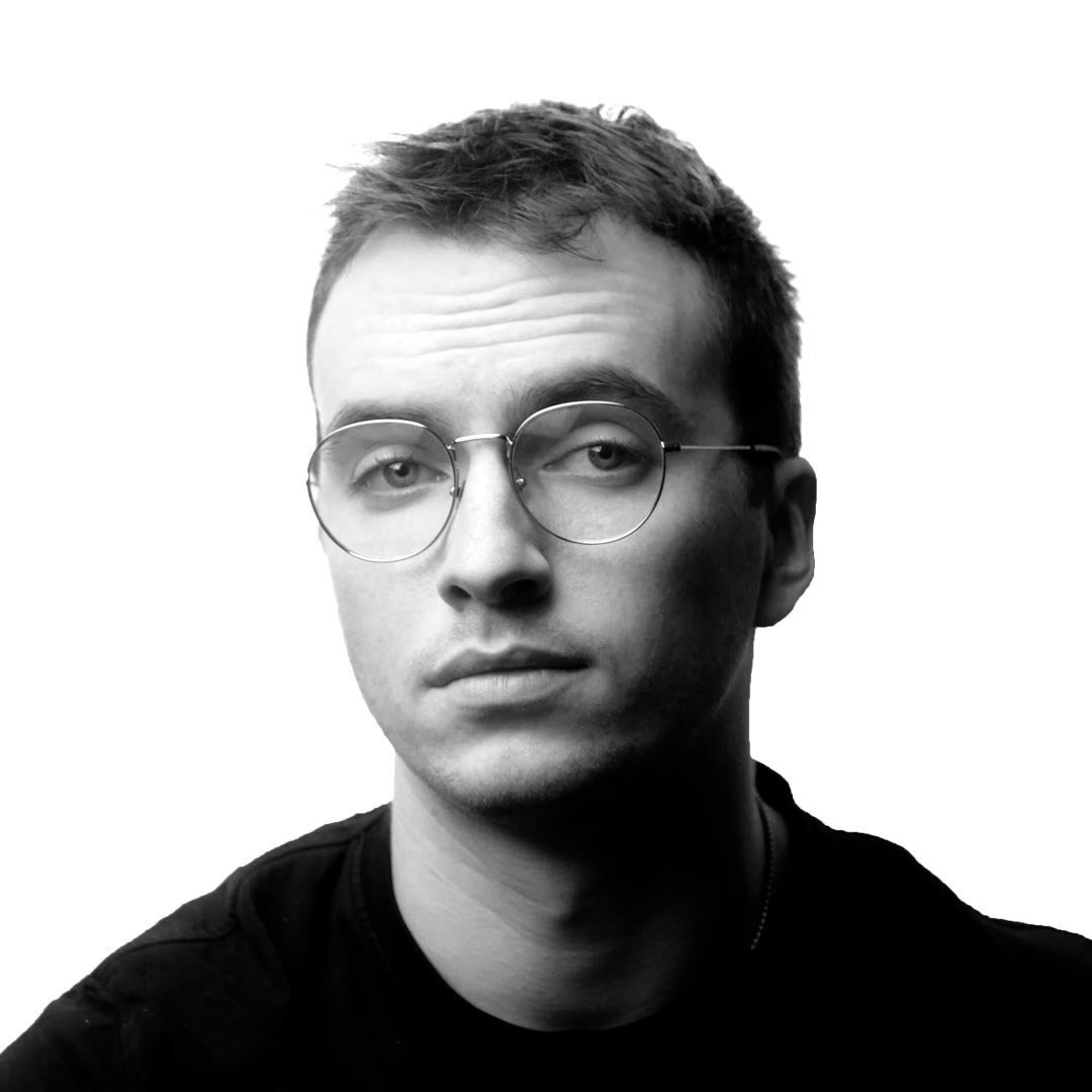 A thoughtful young person with dark hair gazes to the side, captured in soft black and white lighting.