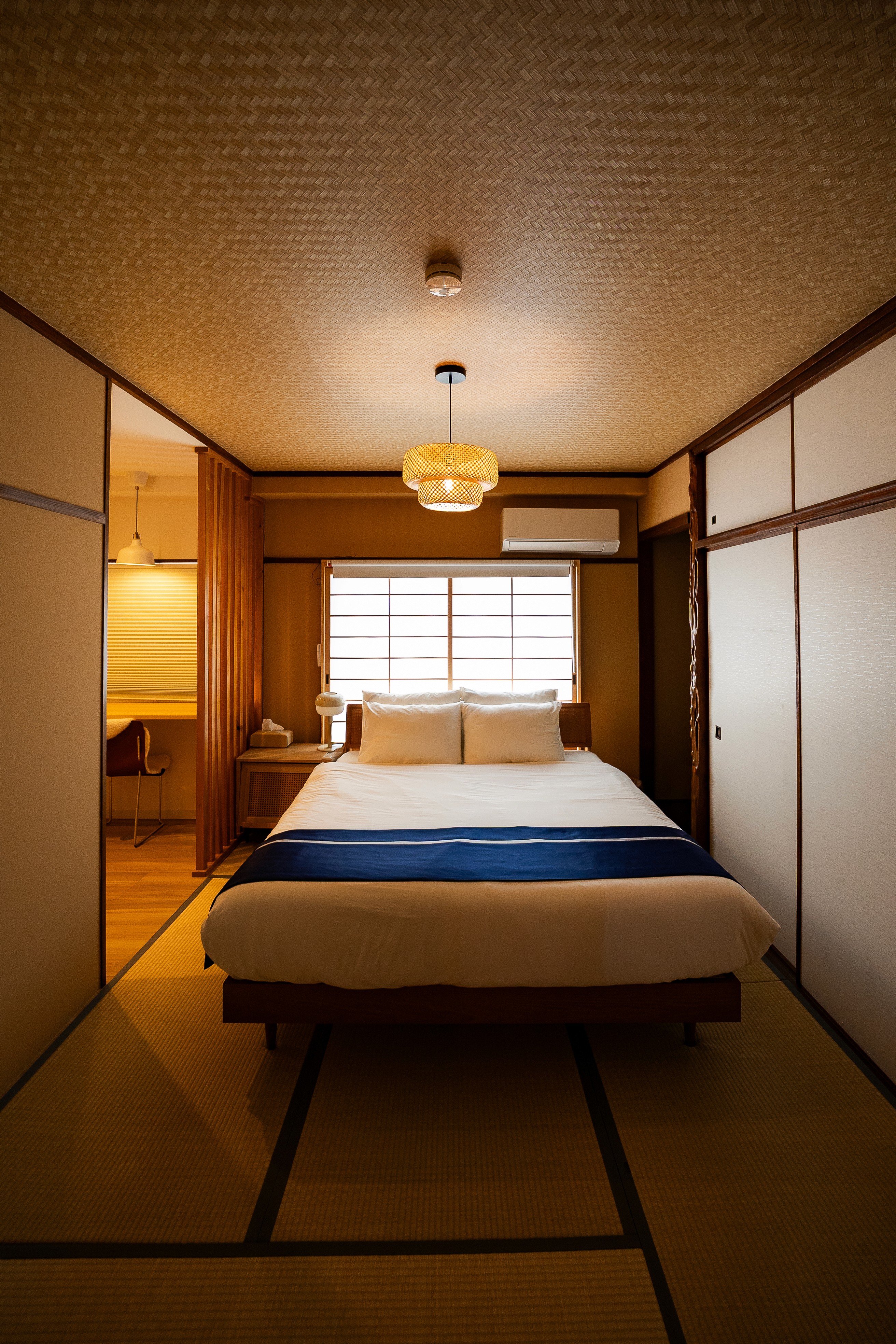 A white-themed traditional bedroom with a table, decorative statue, carpet, and styled artwork.