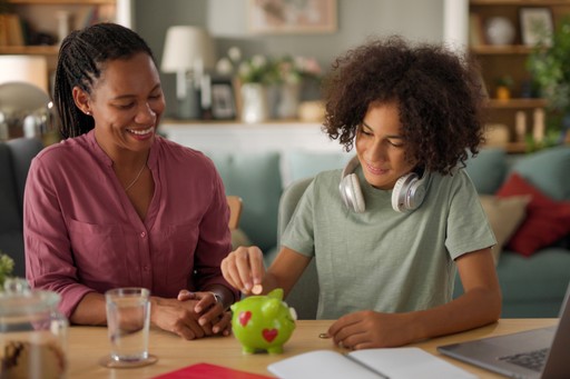 Two women smiling while preparing food together in a kitchen.