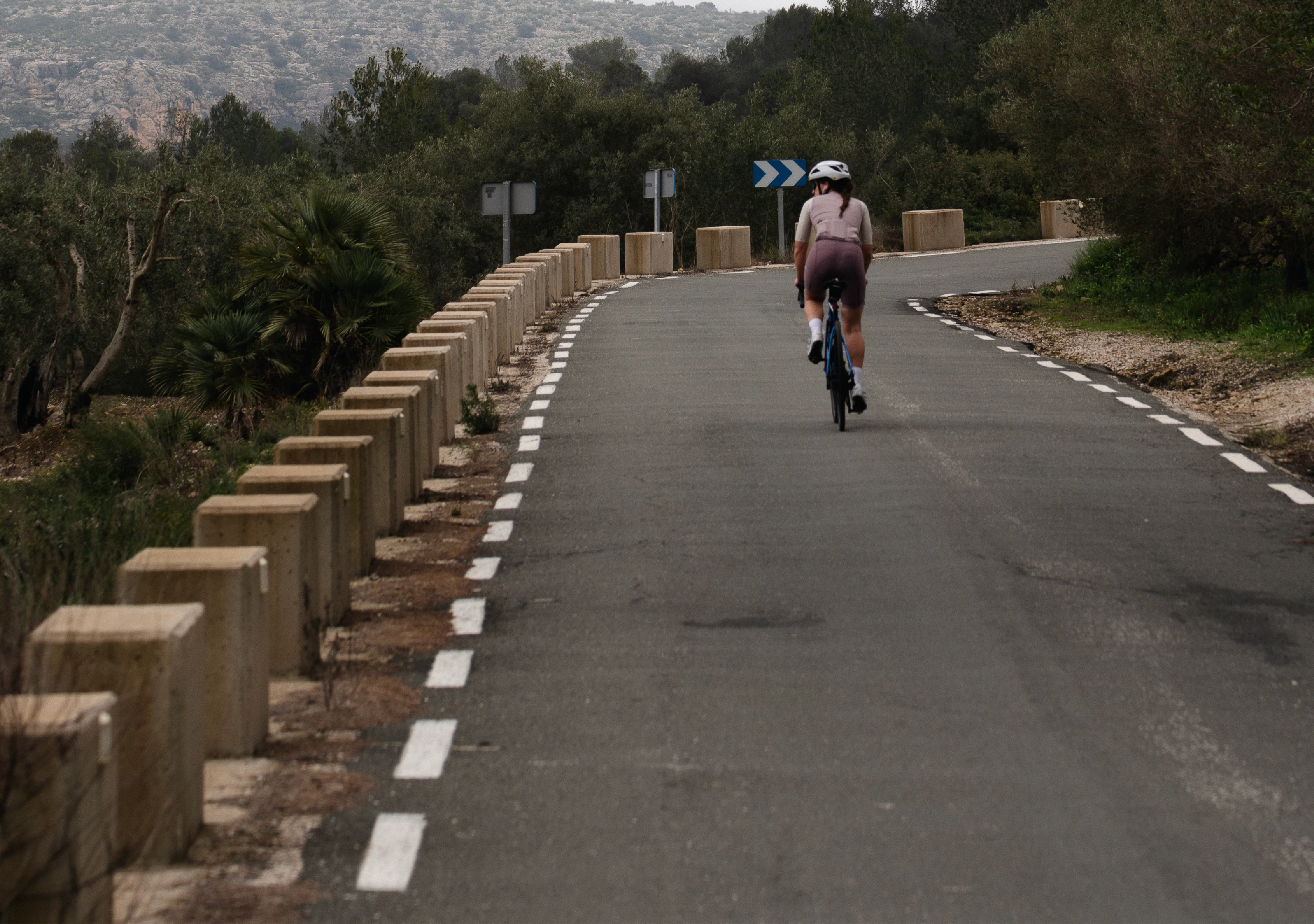 wide shot of a female on a bike looking down the valley.