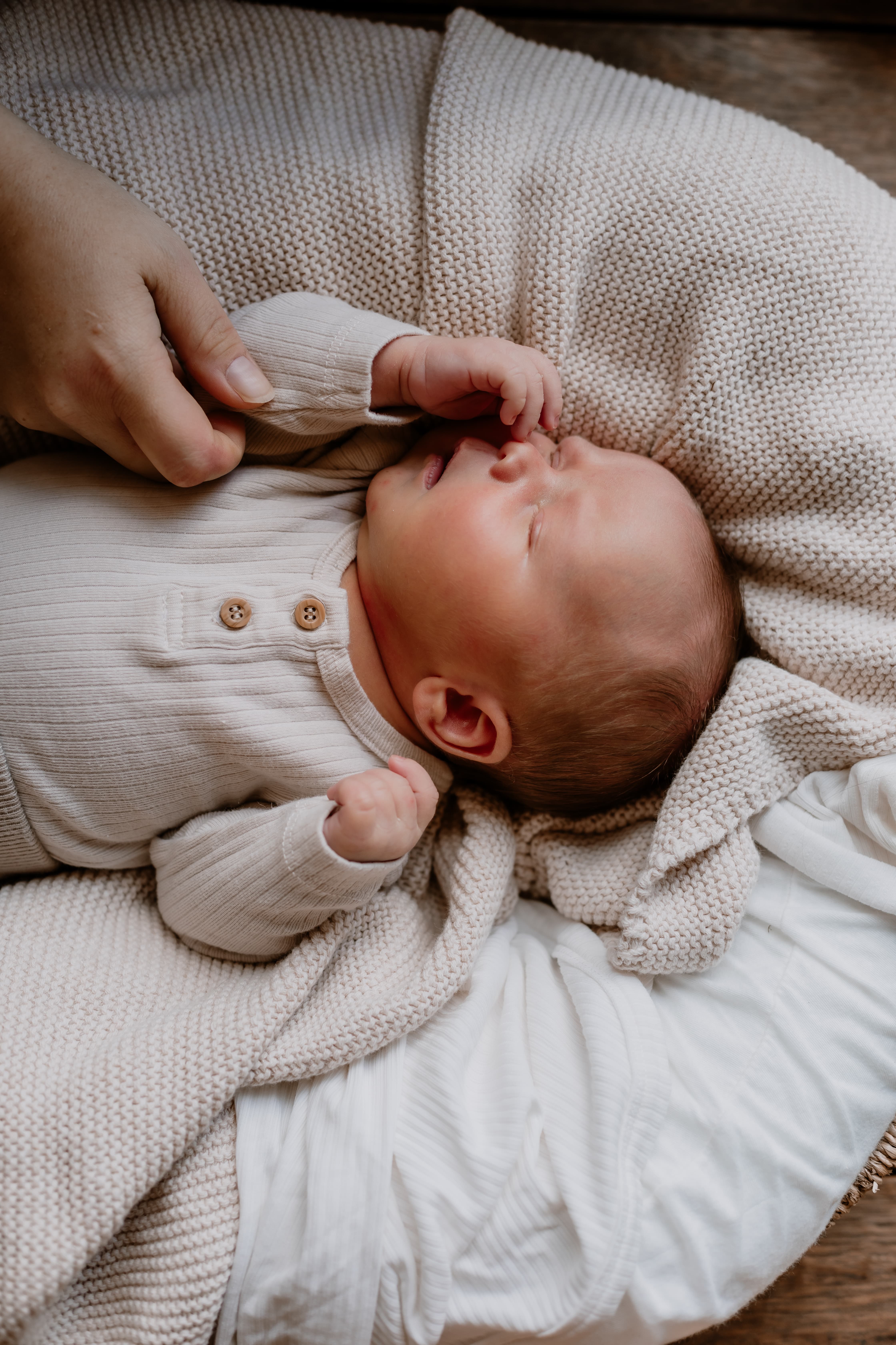 Parent touching newborn baby while sleeping