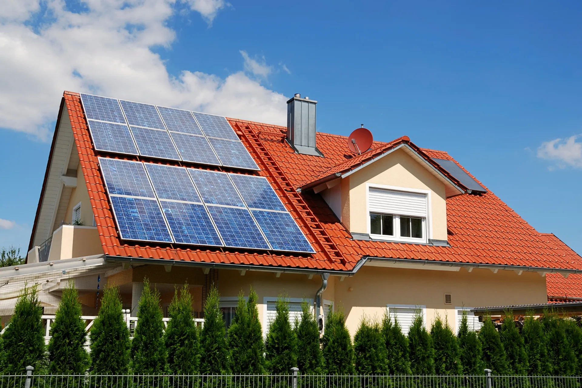 Eine Photovoltaikanlage auf einem roten Dach eines Einfamilienhauses.