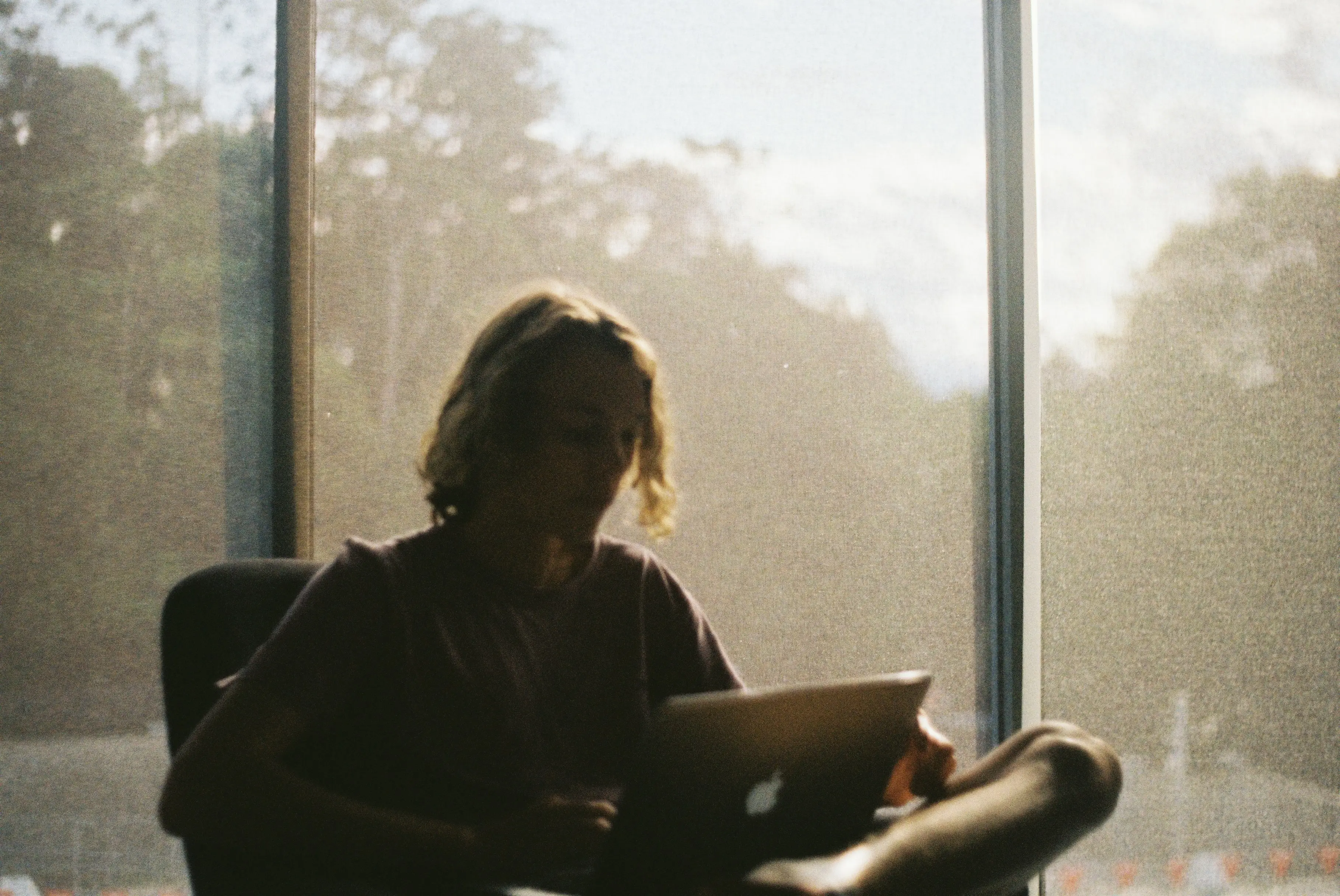 Young male sitting on the couch with an open laptop on his face.