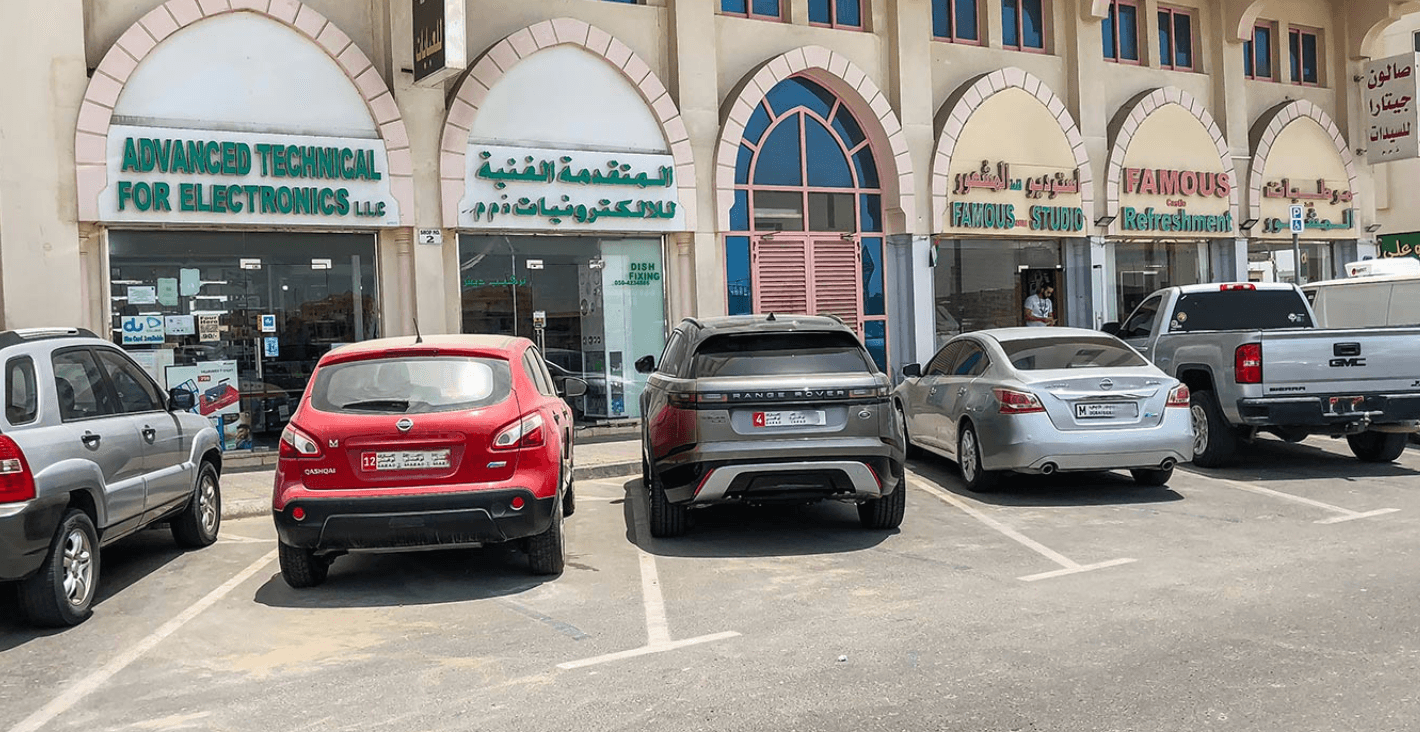 A group of cars parked in front of a building in Khalifa City, showcasing urban architecture and vehicle arrangement.