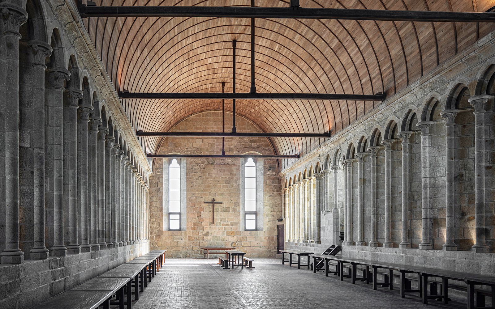 Interior of Mont Saint Michel Abbey with stone columns and arched ceiling.