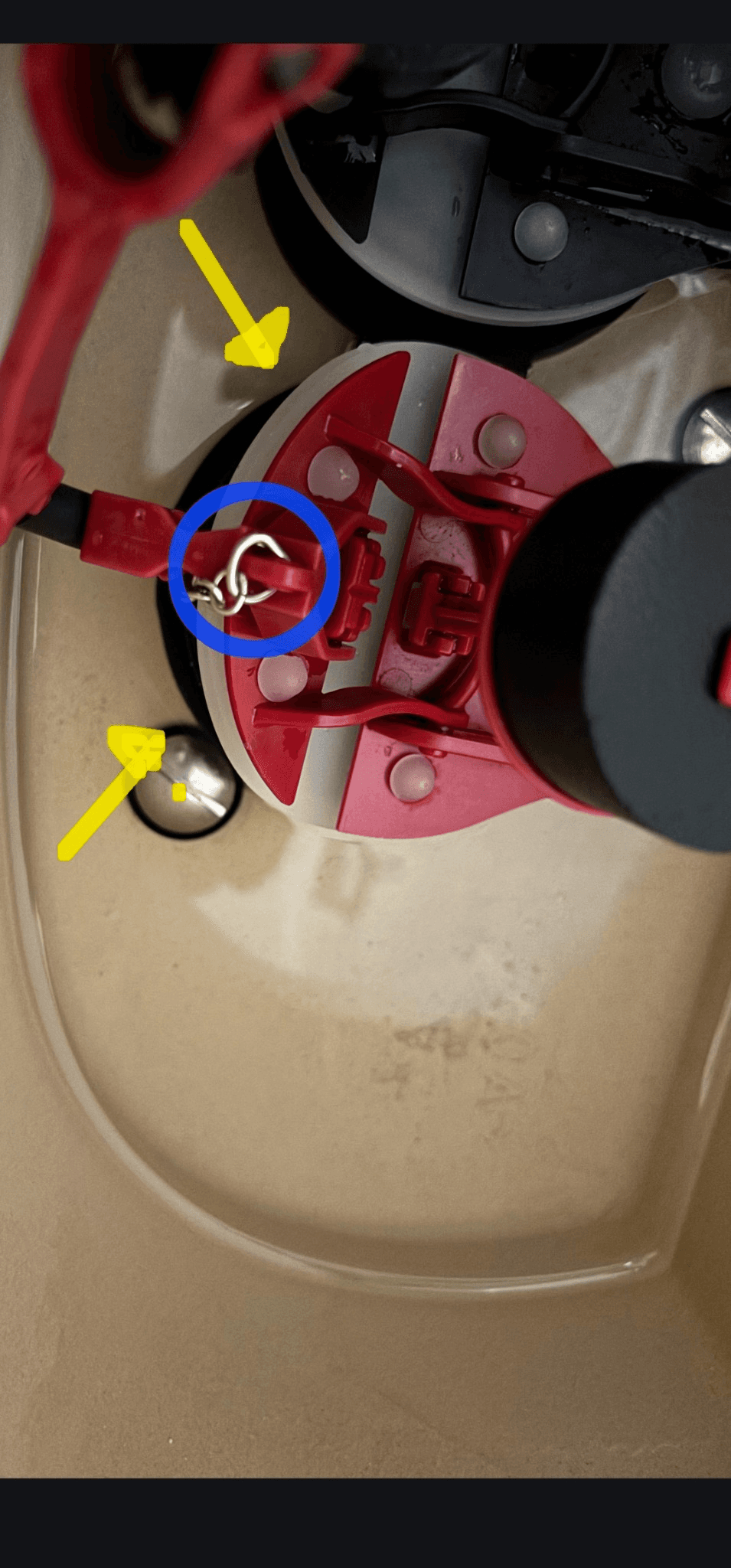 Annotated toilet-tank photo showing the blue-circled chain connection where the chain was tangling and yellow arrows indicating the flapper remaining slightly open.
