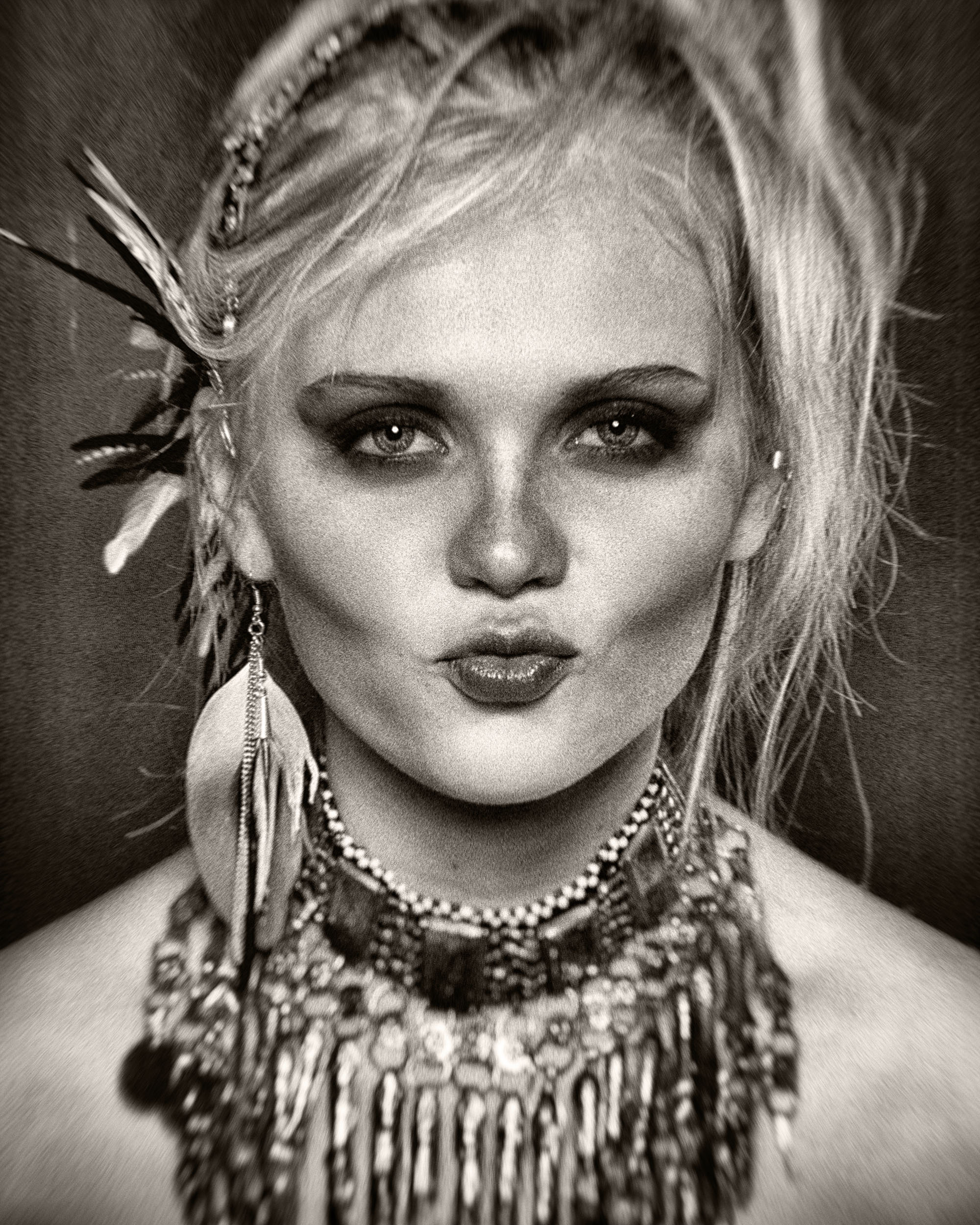 Black and white portrait of Olivia with large necklace and feather earings.