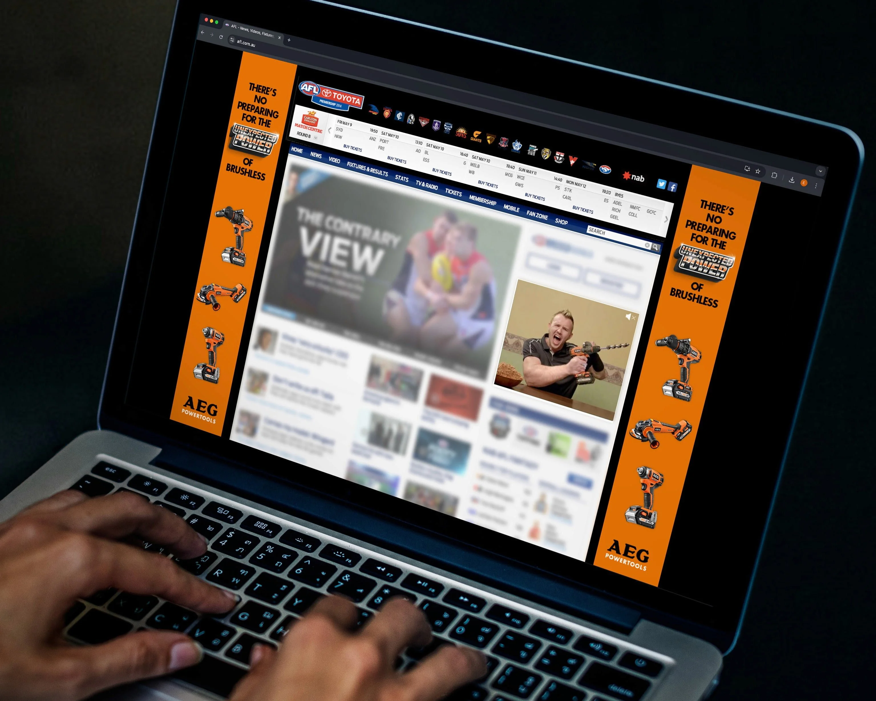 Laptop showing an AFL website framed by orange AEG Powertools banners: 'There's no preparing for the Unexpected Power'
