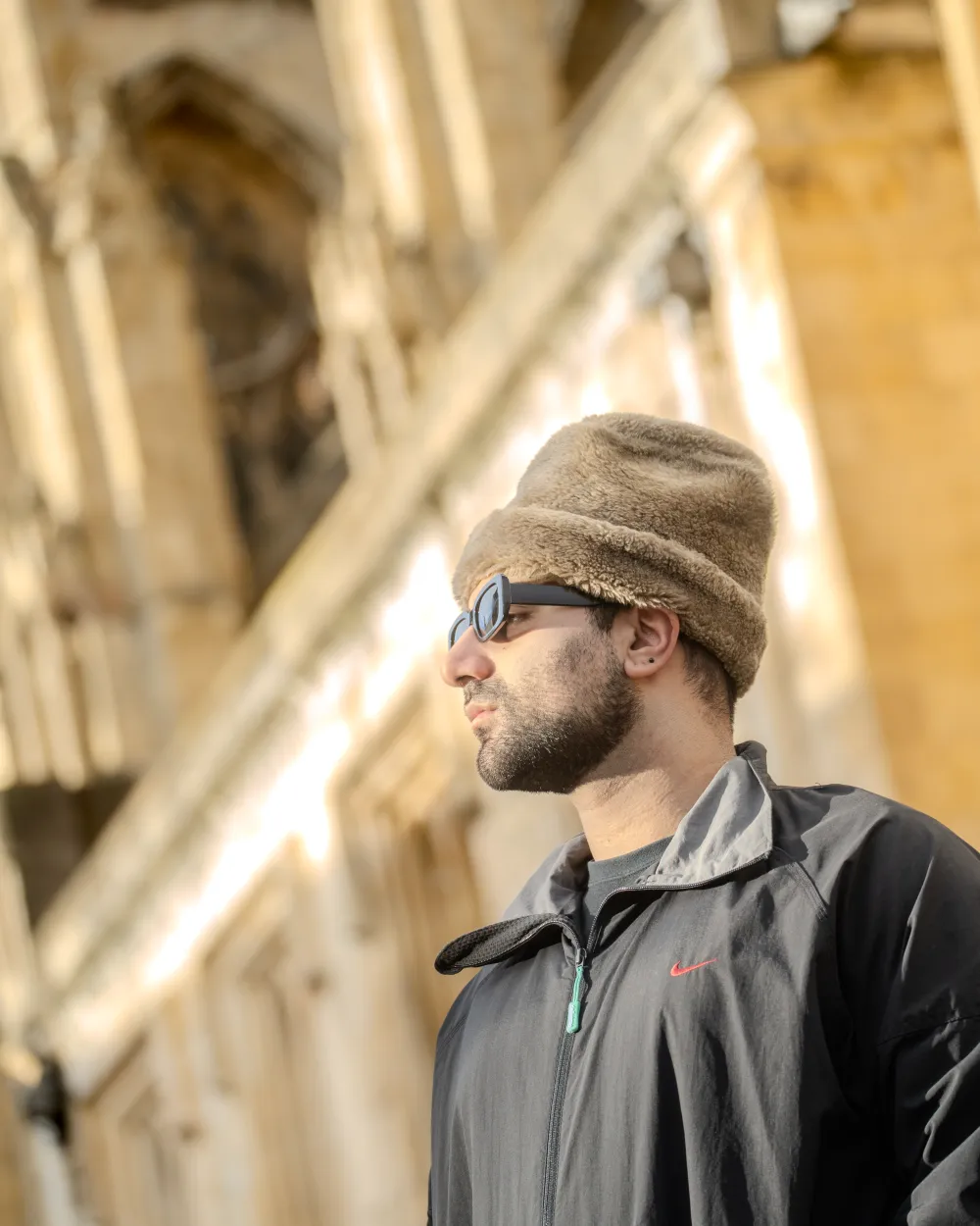 A side-profile portrait of Aria looking towards the sunlight, with the intricate limestone arches of York Minster rising in the background.