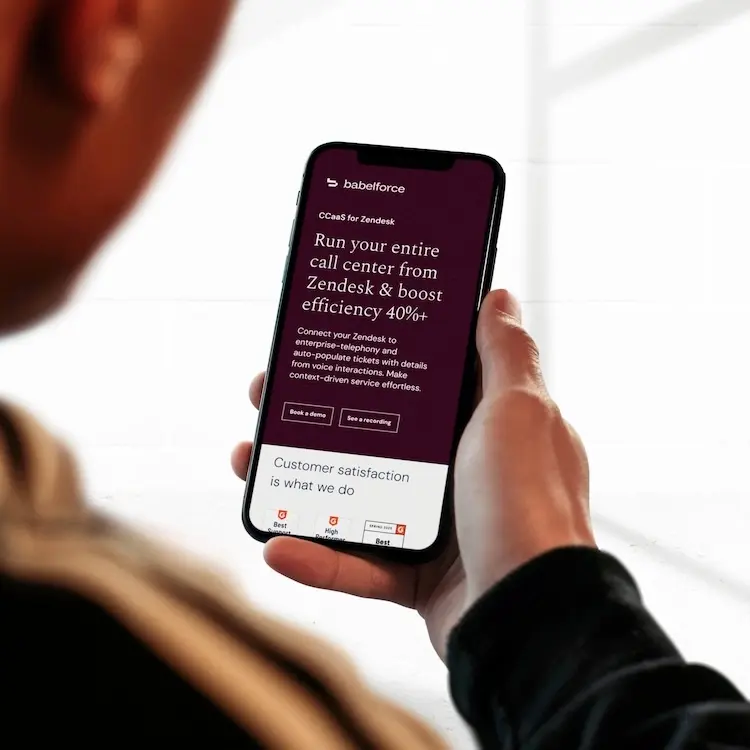 babelforce CCaaS for Zendesk landing page displayed on a mobile phone held in two hands, showing the headline Run your entire call center from Zendesk and boost efficiency 40% plus