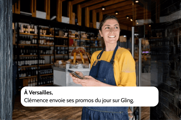 Photo de Clémence à Versailles, devant son commerce, utilisant son téléphone pour envoyer ses promotions du jour sur Gling et informer ses clients locaux.