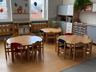 Světlá třída s kulatými stolky a dřevěným nábytkem