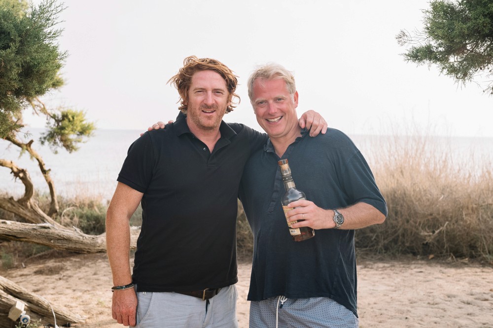 Two people outdoors, one holding a bottle with a premium cork stopper, showcasing spirits packaging and whisky closures.
