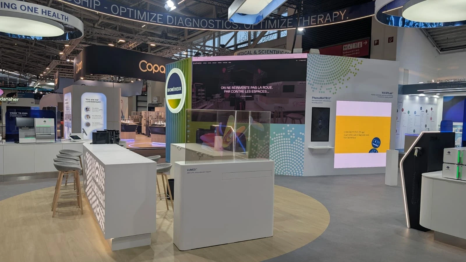 Stand bioMérieux conçu et réalisé par Expace pour le congrès ESCMID Global 2026 à Munich – stand sur-mesure de diagnostic médical avec anneaux lumineux, comptoirs d'accueil et espaces de démonstration.