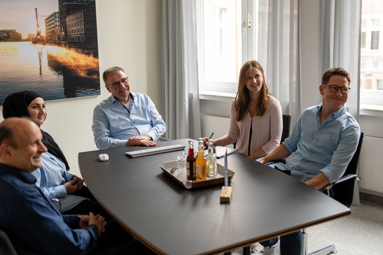 Runde Besprechung bei SLB: Mehrere Personen sitzen an einem Konferenztisch und diskutieren gemeinsam.