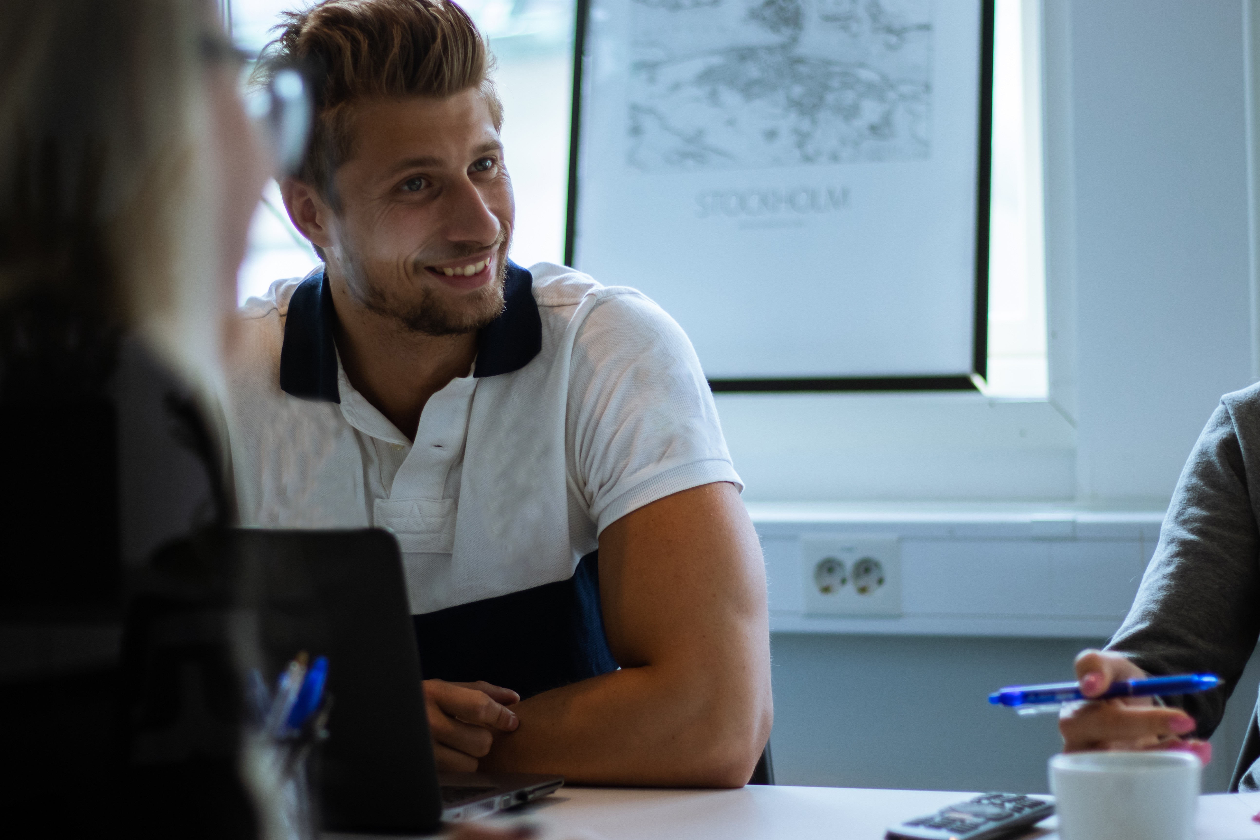 Smiling man and woman sitting on a couch, chatting in warm natural light with a plant nearby