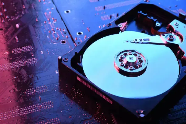 An aesthetic shot of a spinning disk hard drive under blue and red lighting.