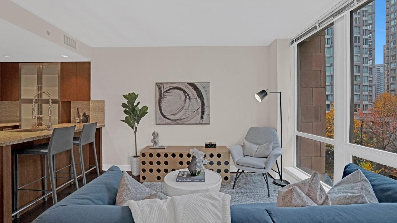 Modern living room with a couch, coffee table, and large windows showing a city view. Warm, inviting decor.