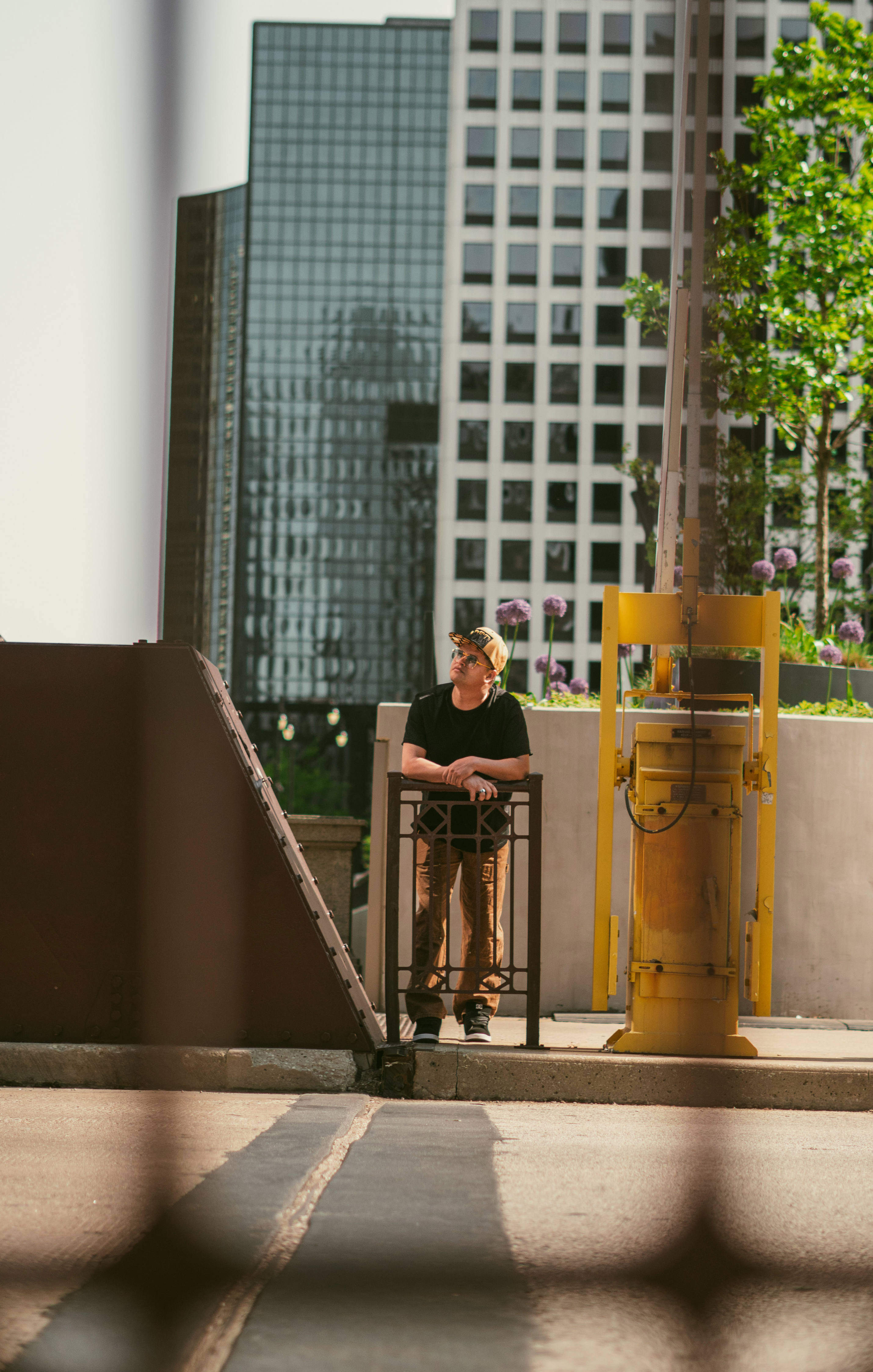Dani Sierra stands on a stairway in an urban setting, framed by architectural elements and greenery.