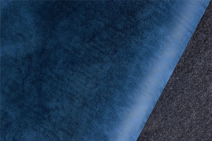 Hand burnishing leather edge with wooden tool in workshop