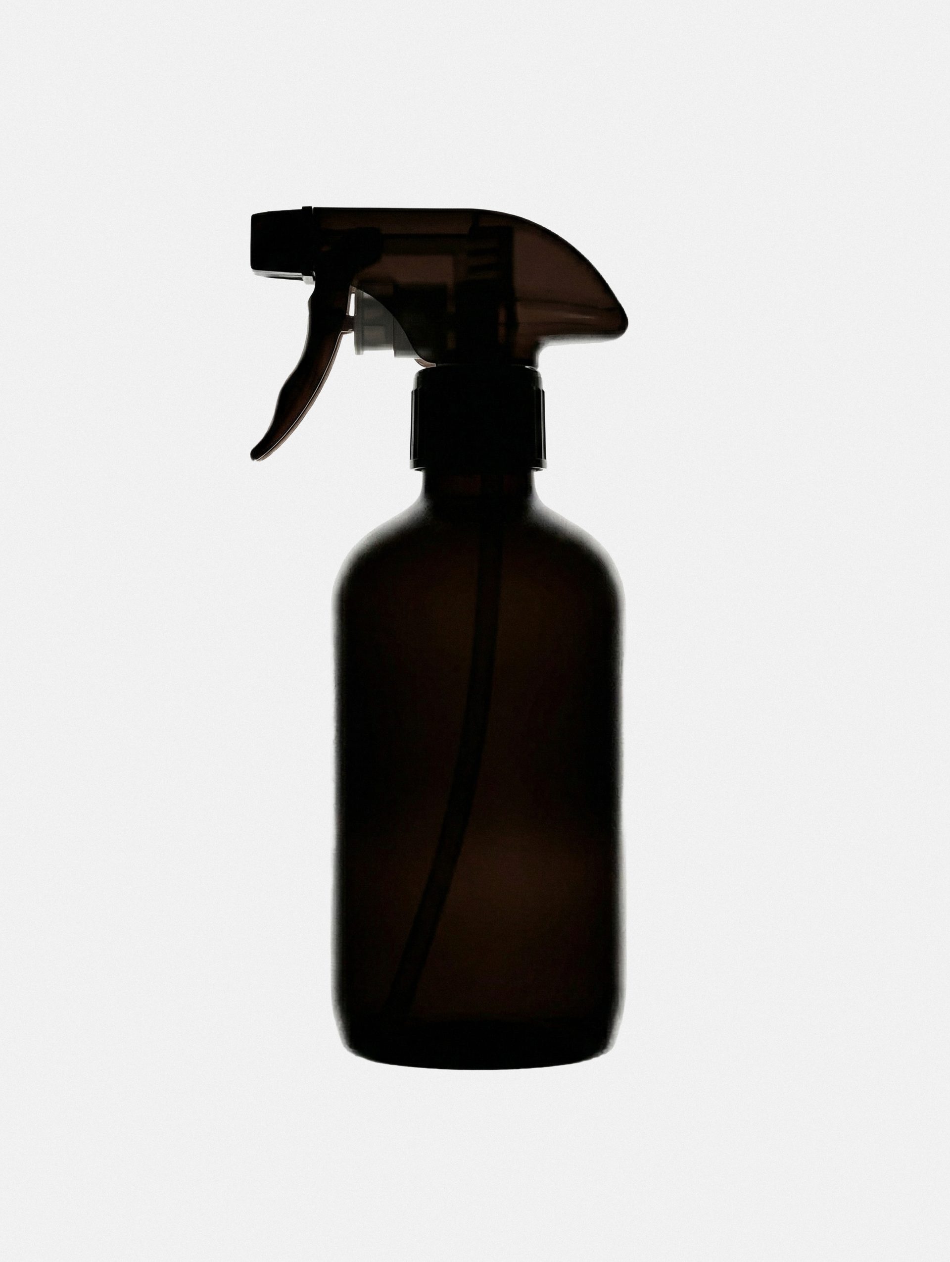 Minimal amber spray bottle silhouette on white