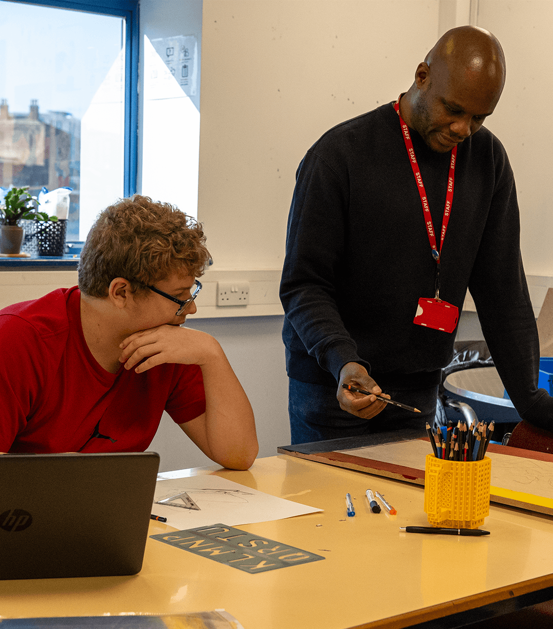 Mentor assisting a student with schoolwork, guiding him through explanations while both look at the mentor's work