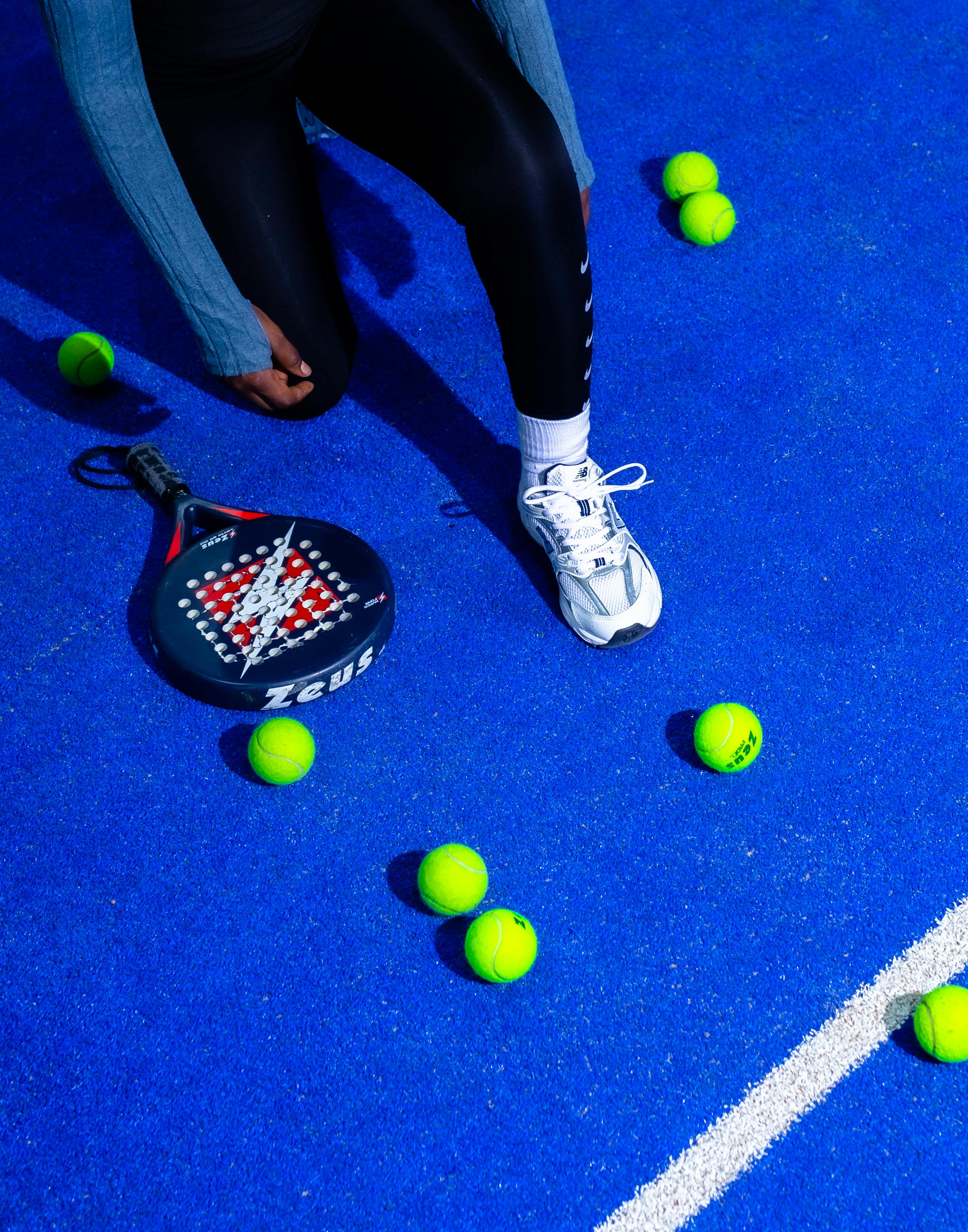 A woman sitting on the ground next to a tennis racket