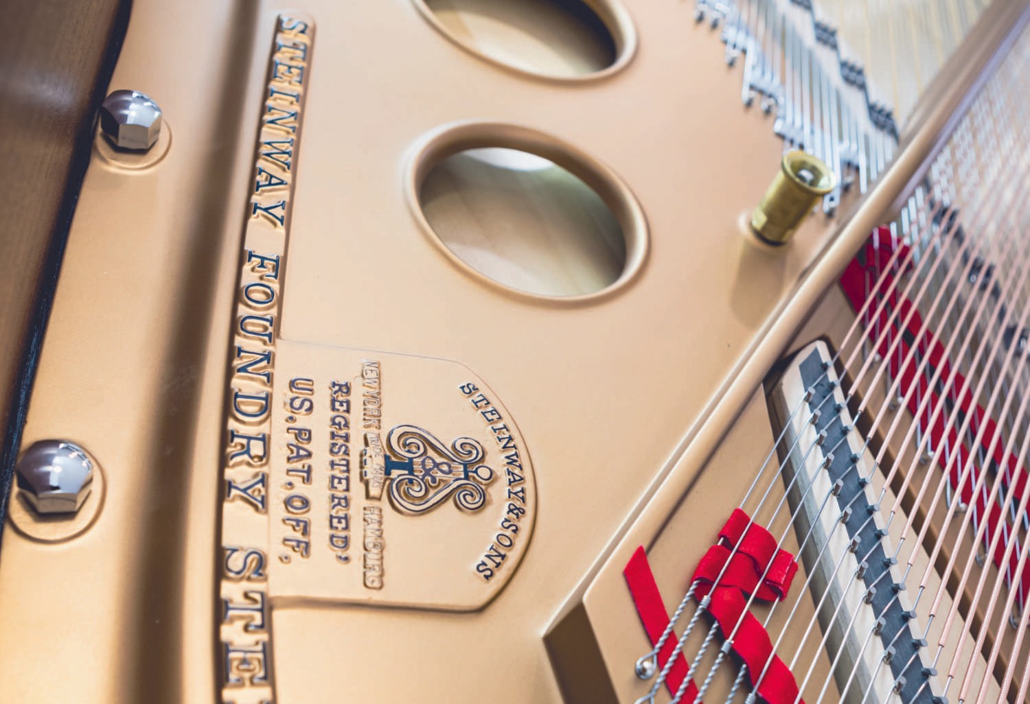 A detailed view of the pristine white grand piano’s interior, showcasing golden hardware and finely arranged strings.