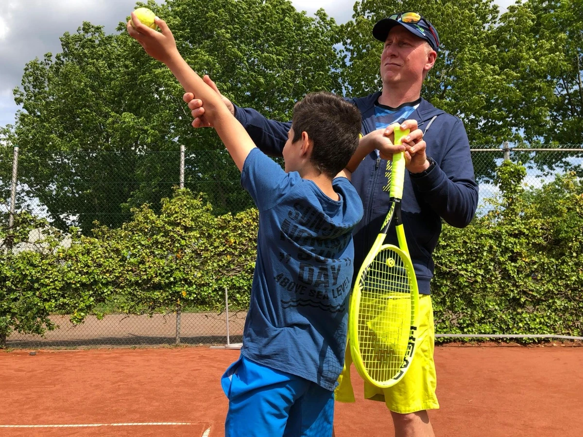person in black shorts holding green tennis racket