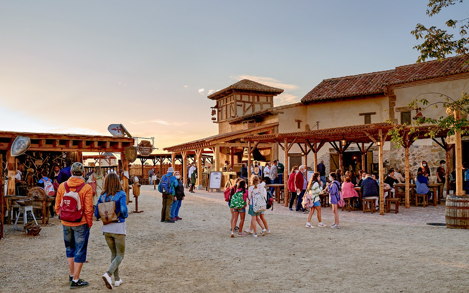 Visitors exploring Puy du Fou España park with rustic buildings and outdoor seating.