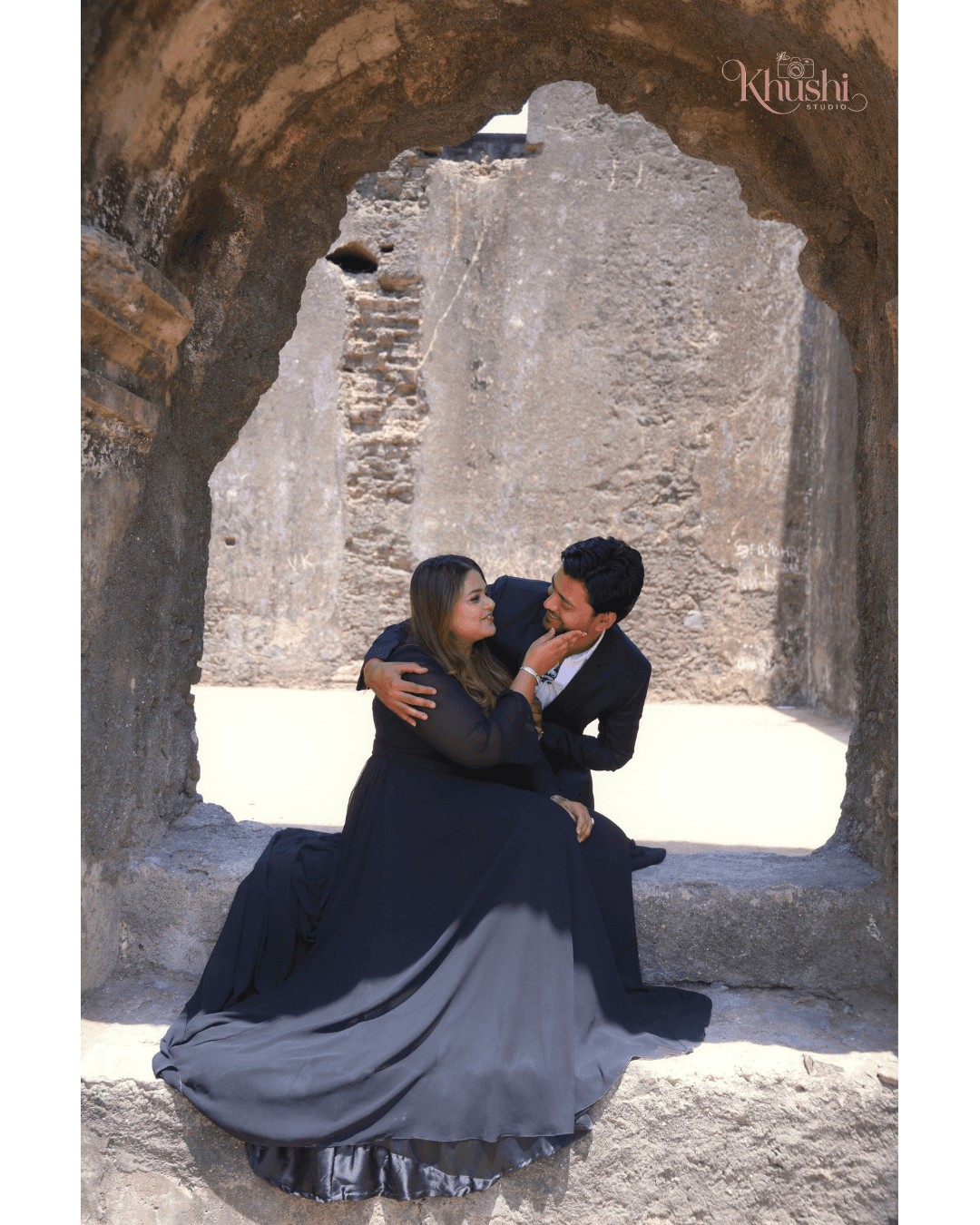 A couple joyfully celebrates in front of a rustic stone building.