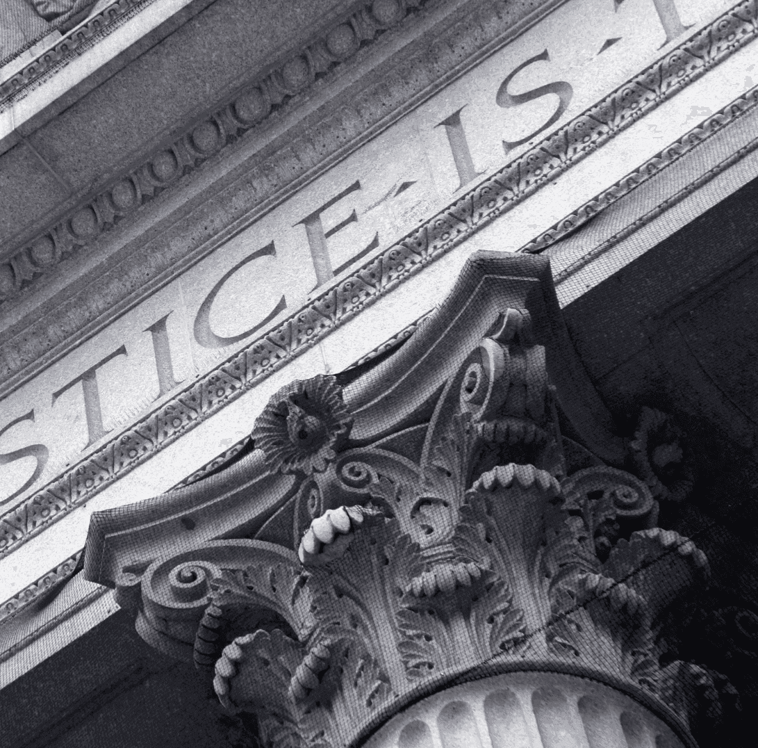 Smiling man in a maroon sweater working at a computer in a modern, industrial-looking lab or tech workspace.