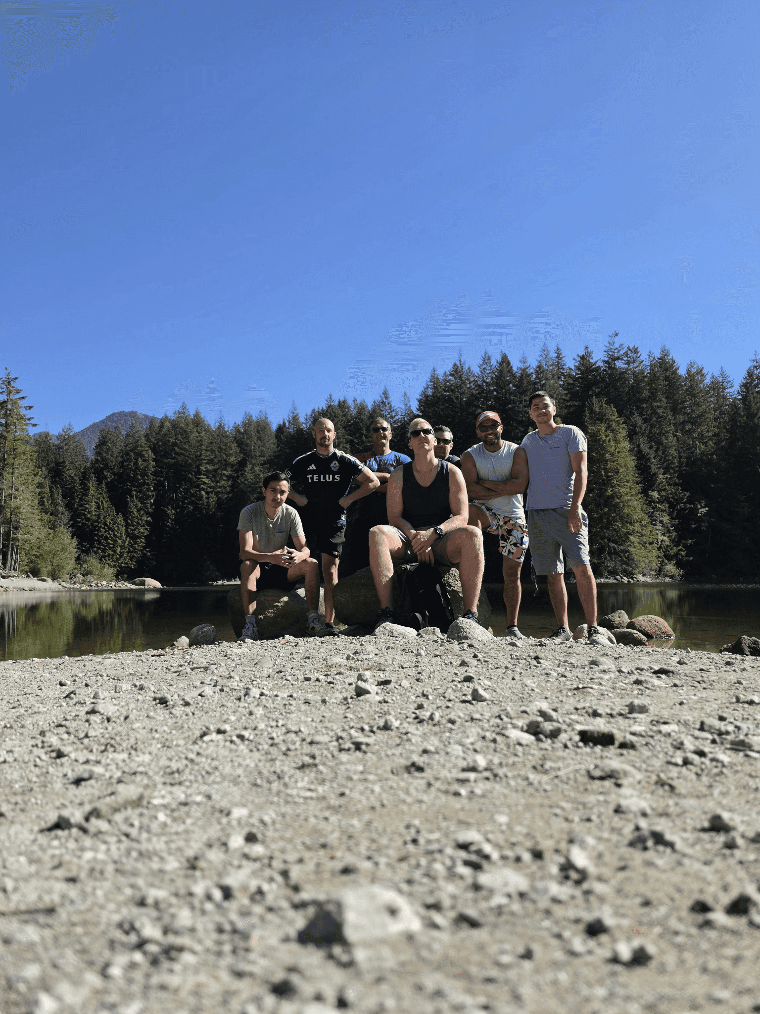 A group of men posing beside a lake during a hiking outing.