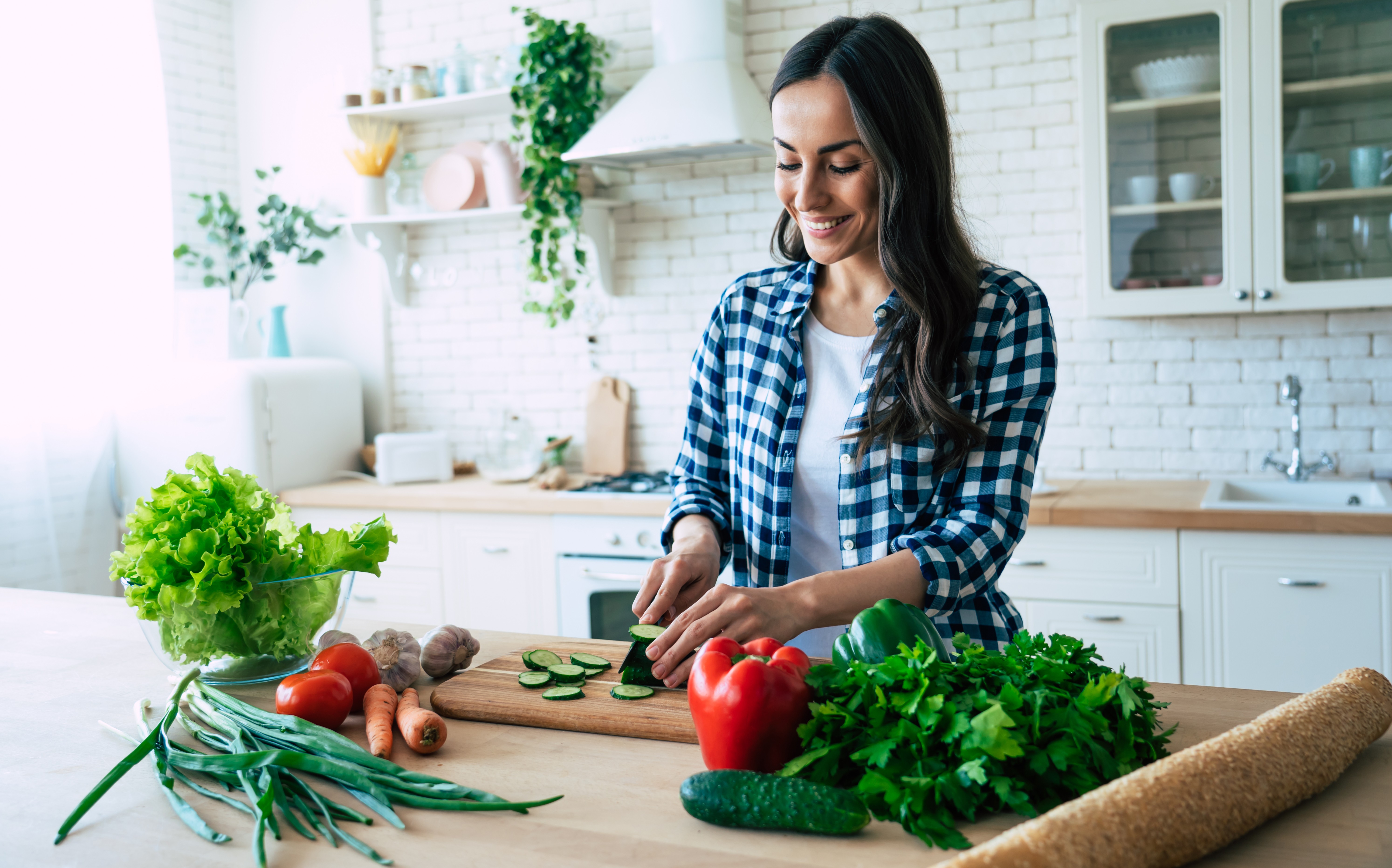 A women standing in a kitchn chopping vegetables and leafy greens for a healthy meal