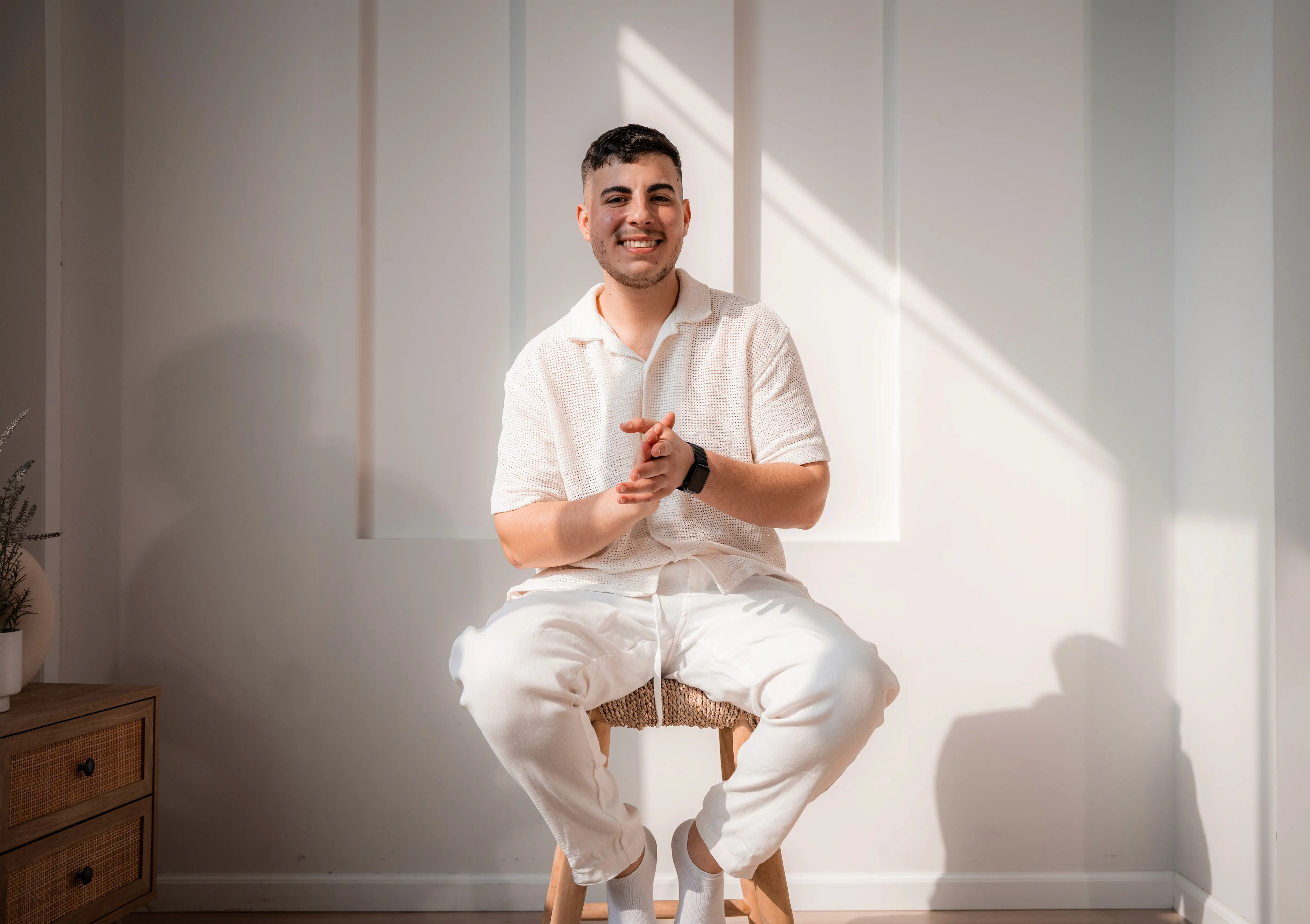 smiling man sitting on gray rock at daytime