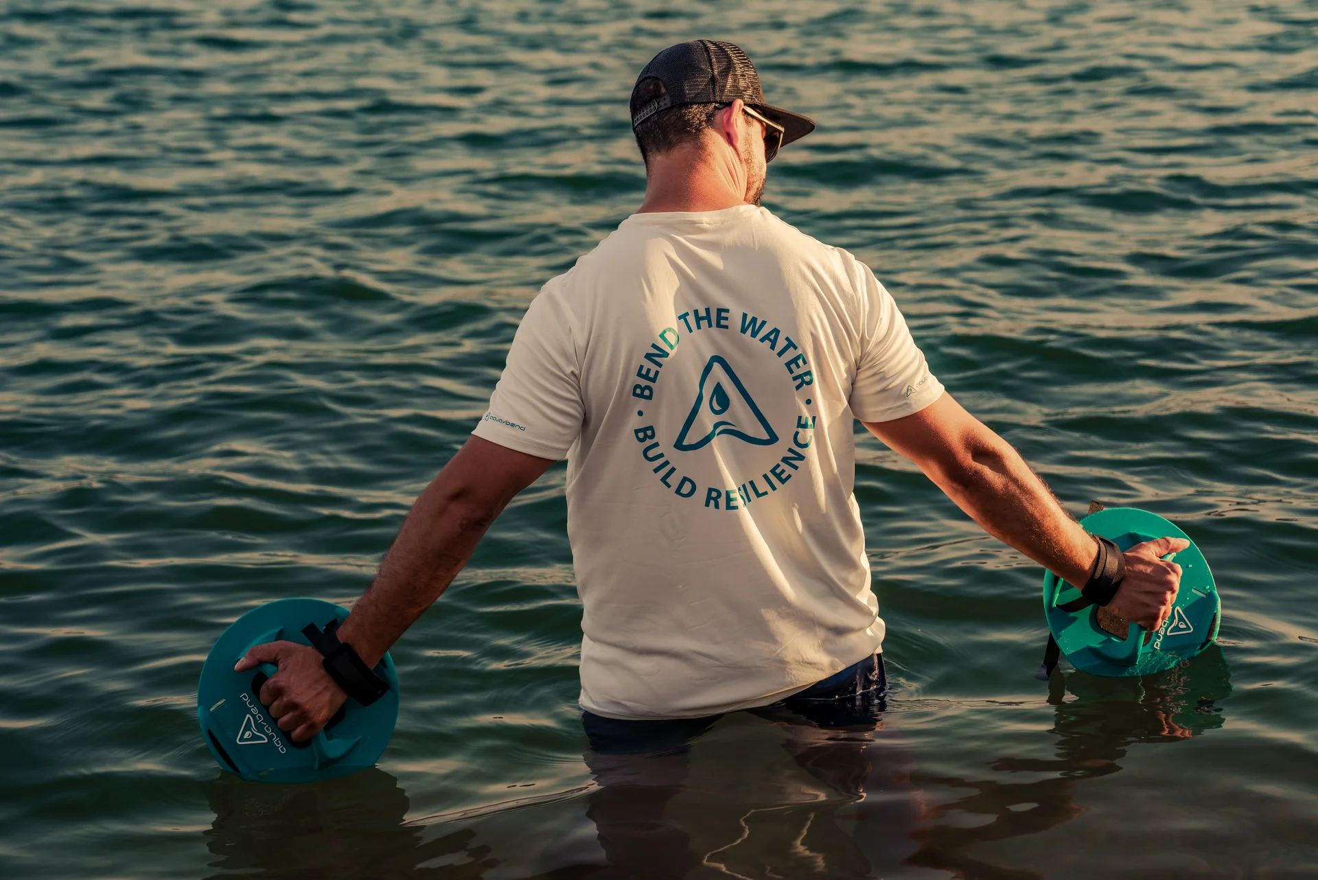 Man standing calmly in water with Aqua-Bend discs lightly submerged, enjoying stillness and sunlight