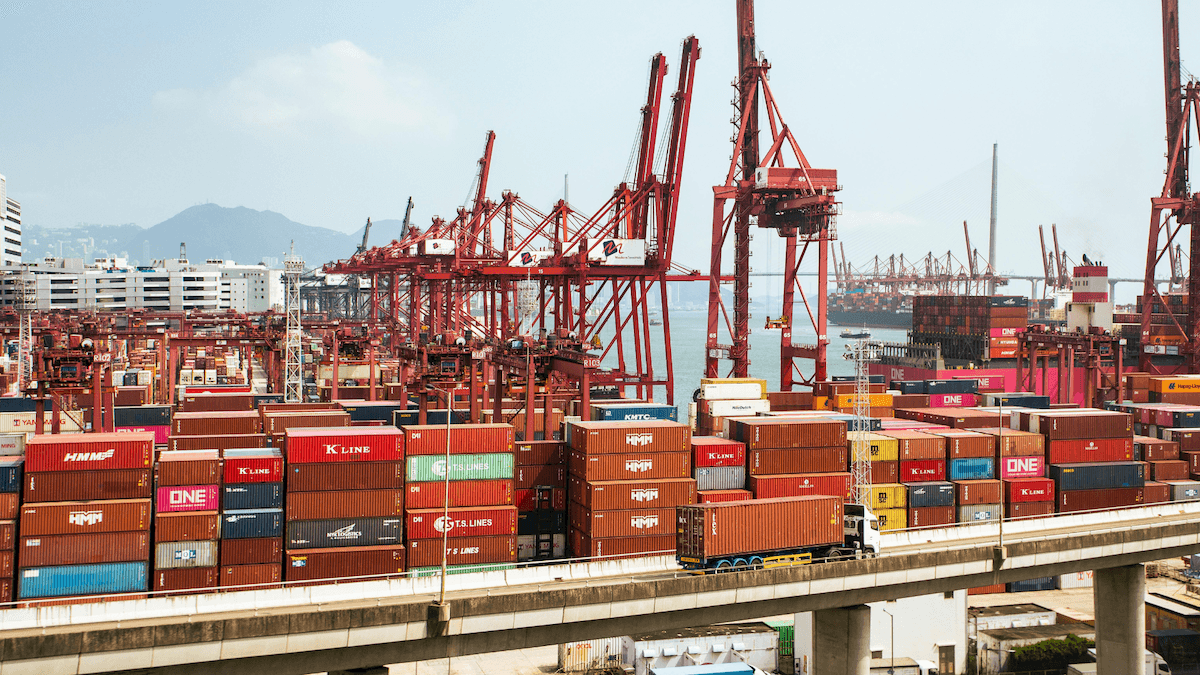 Busy container terminal port with red cranes and stacked shipping containers ready for export.