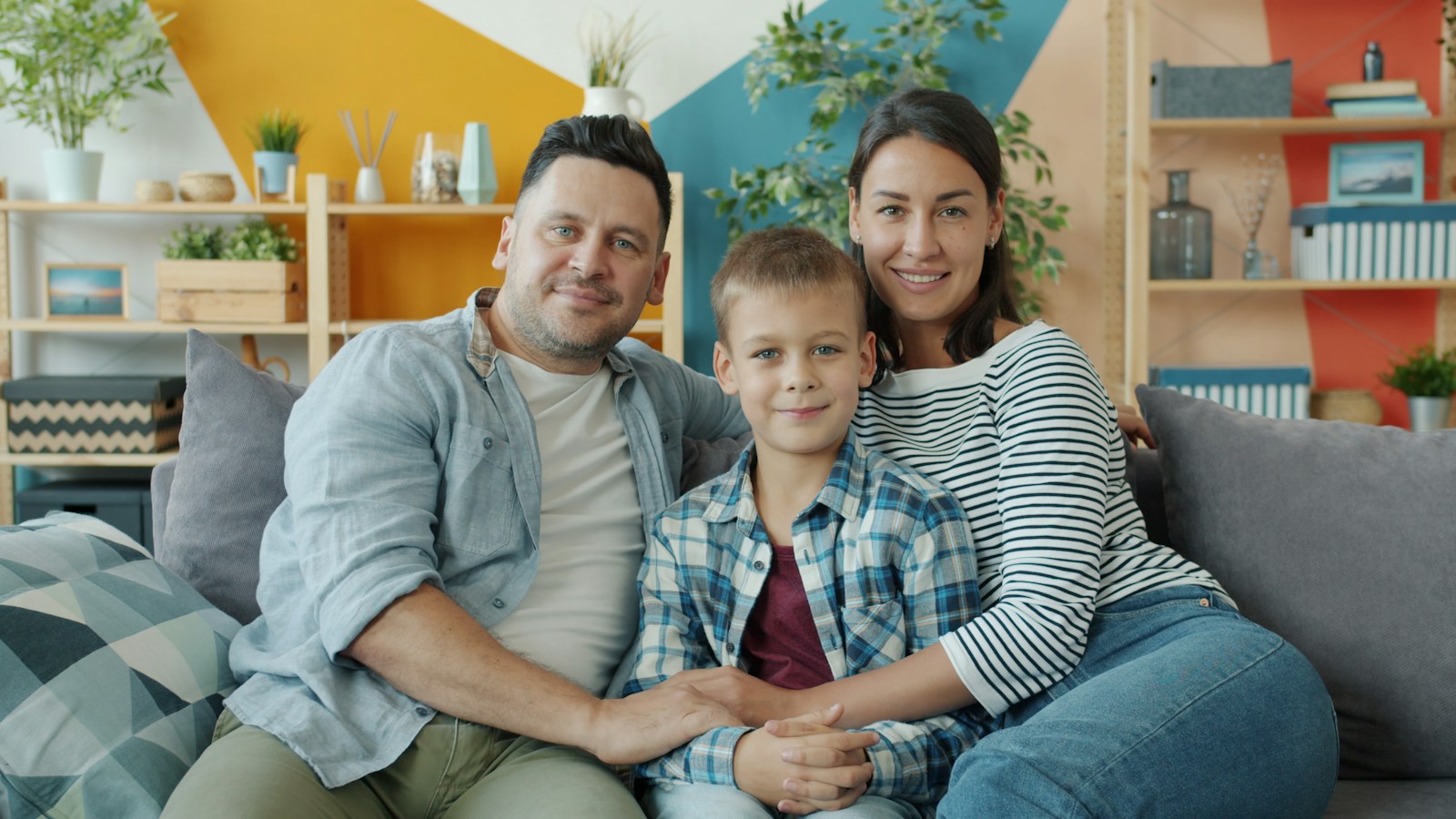 Family of three sitting together on a sofa at home