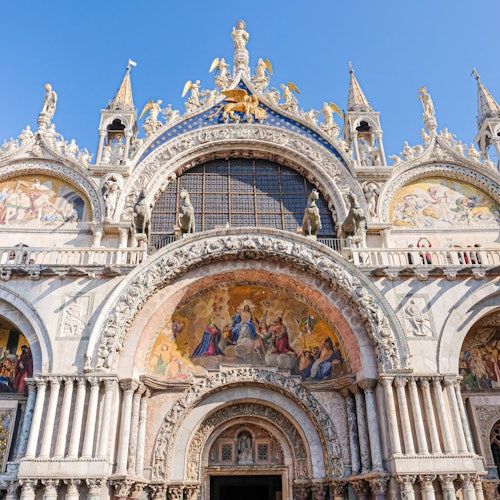 Elaborata facciata della cattedrale con archi ornati, sculture dettagliate e mosaici colorati sotto un cielo azzurro limpido.
