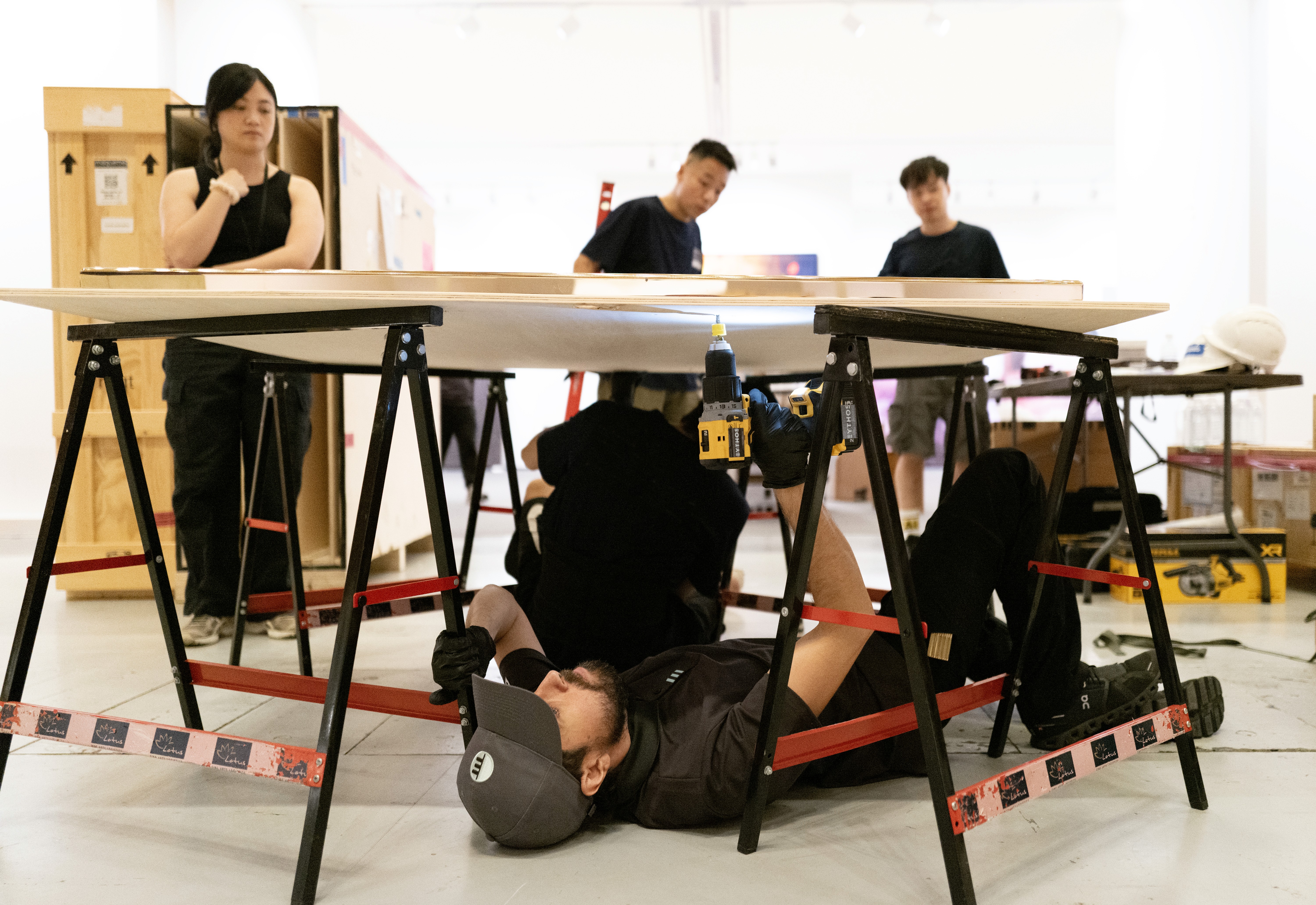 Eythos art technician going above... and below to install an artwork in the Gagosian booth at Frieze Seoul 2024