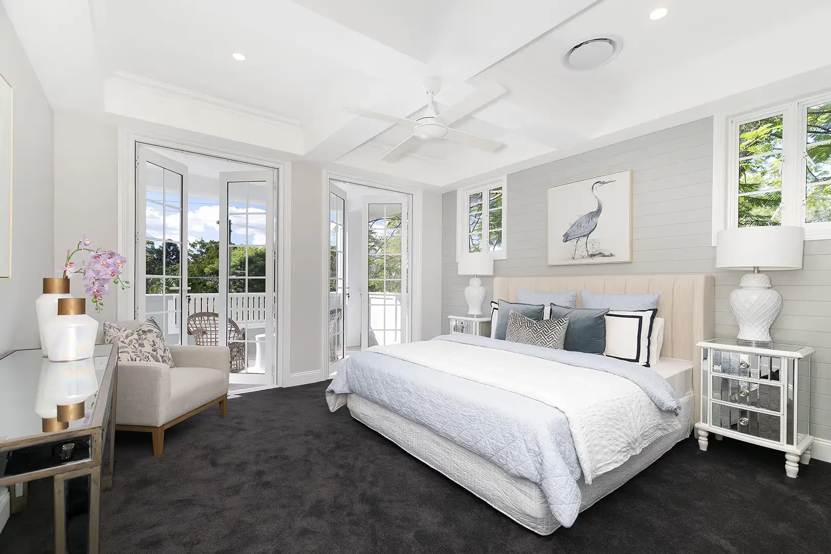 A luxurious master bedroom with coffered ceilings and doors that open onto the balcony