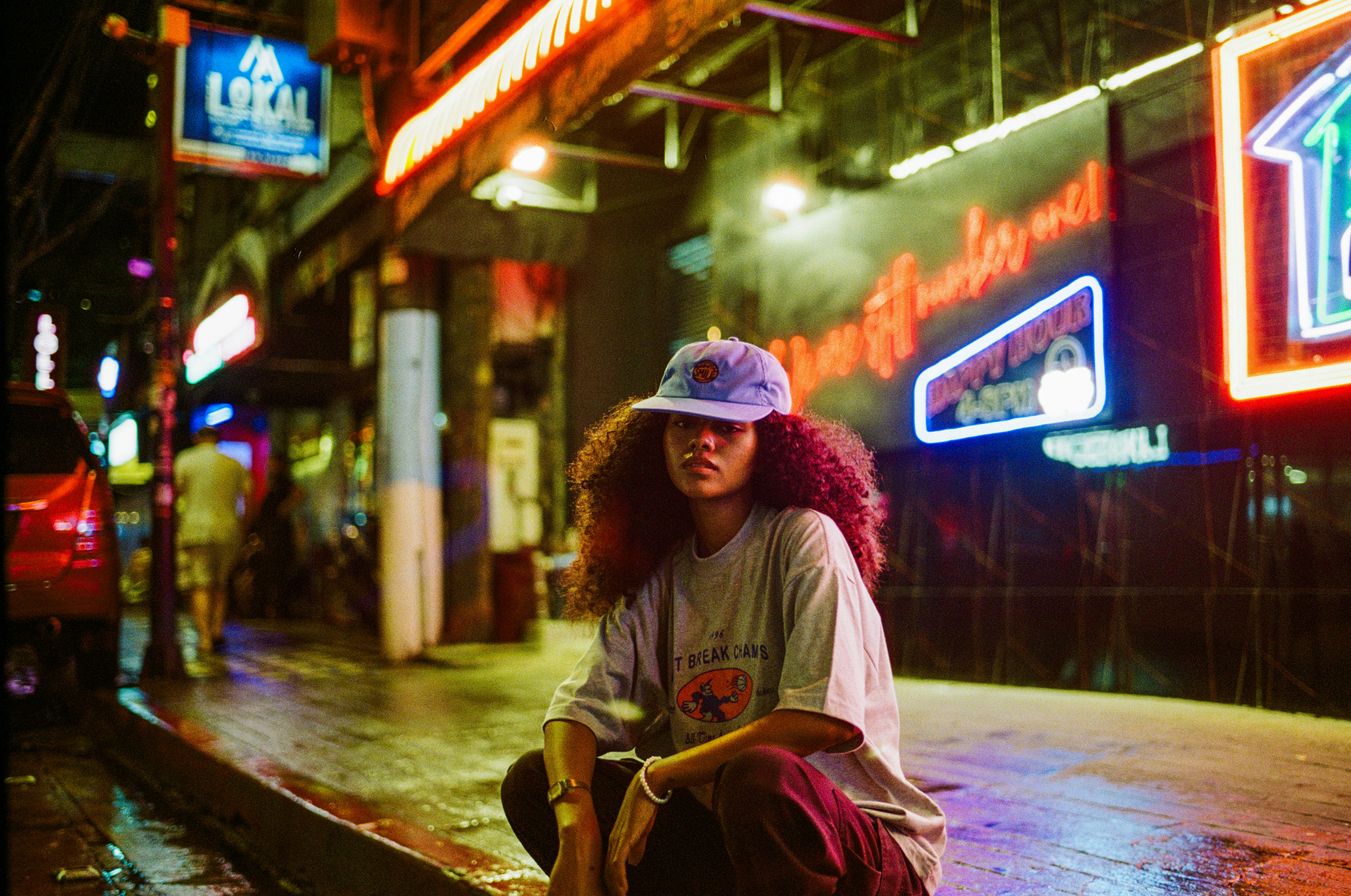 young woman wearing a cap and t-shirt sat on the kerb