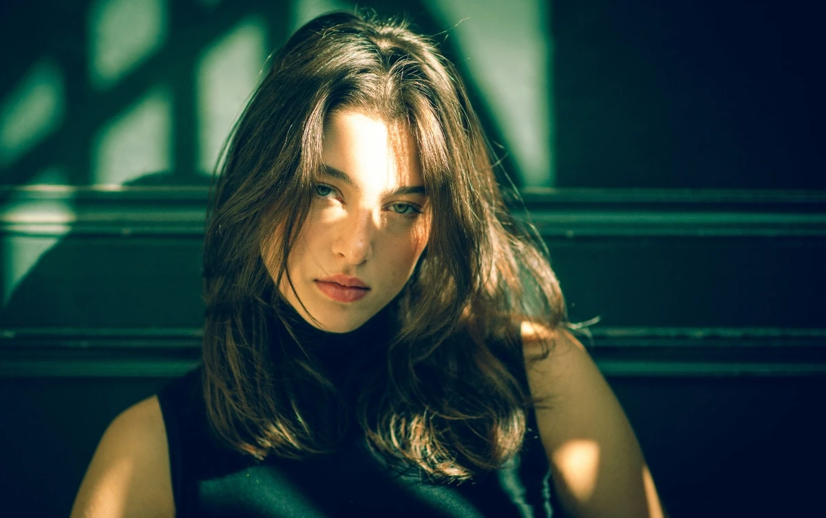 a man in a black hoodie standing in front of a tree