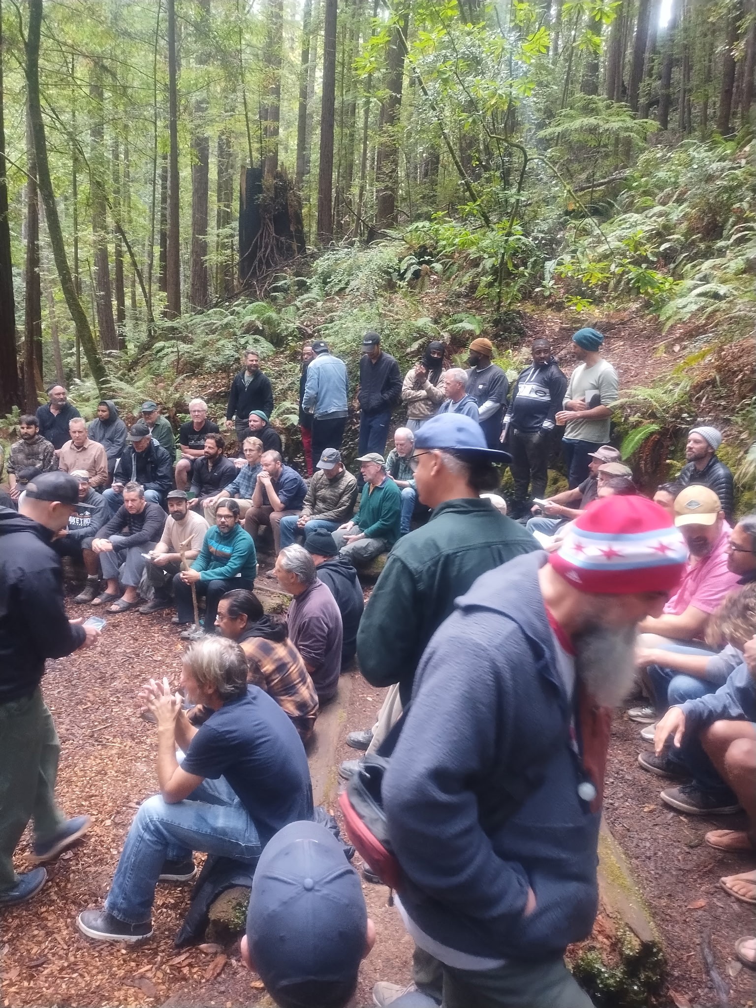 Man in motion during a yoga session in a light-filled modern room with large windows, wood floors, greenery visible outside