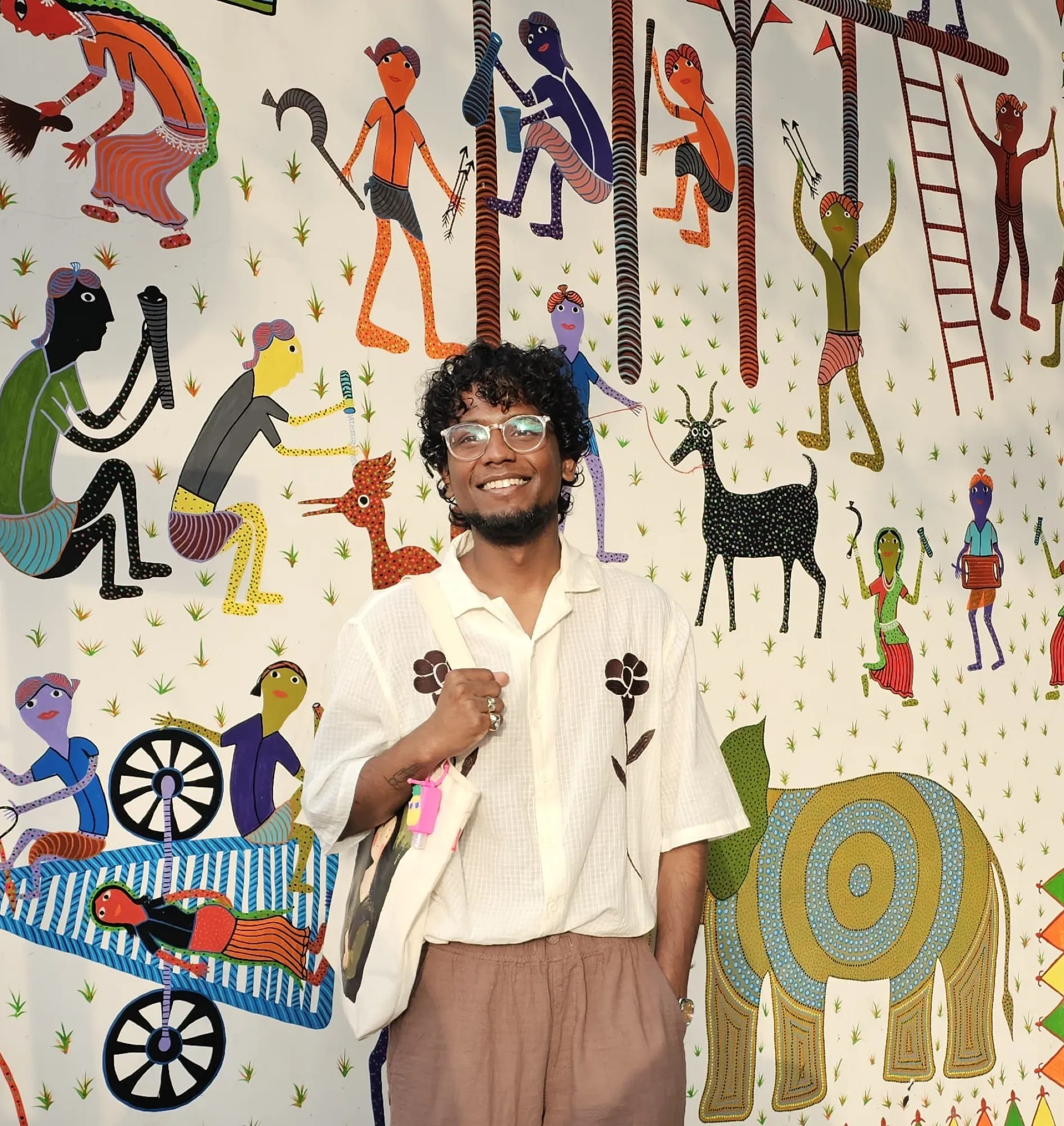 Aayush, the illustrator, smiling in front of a painted mural