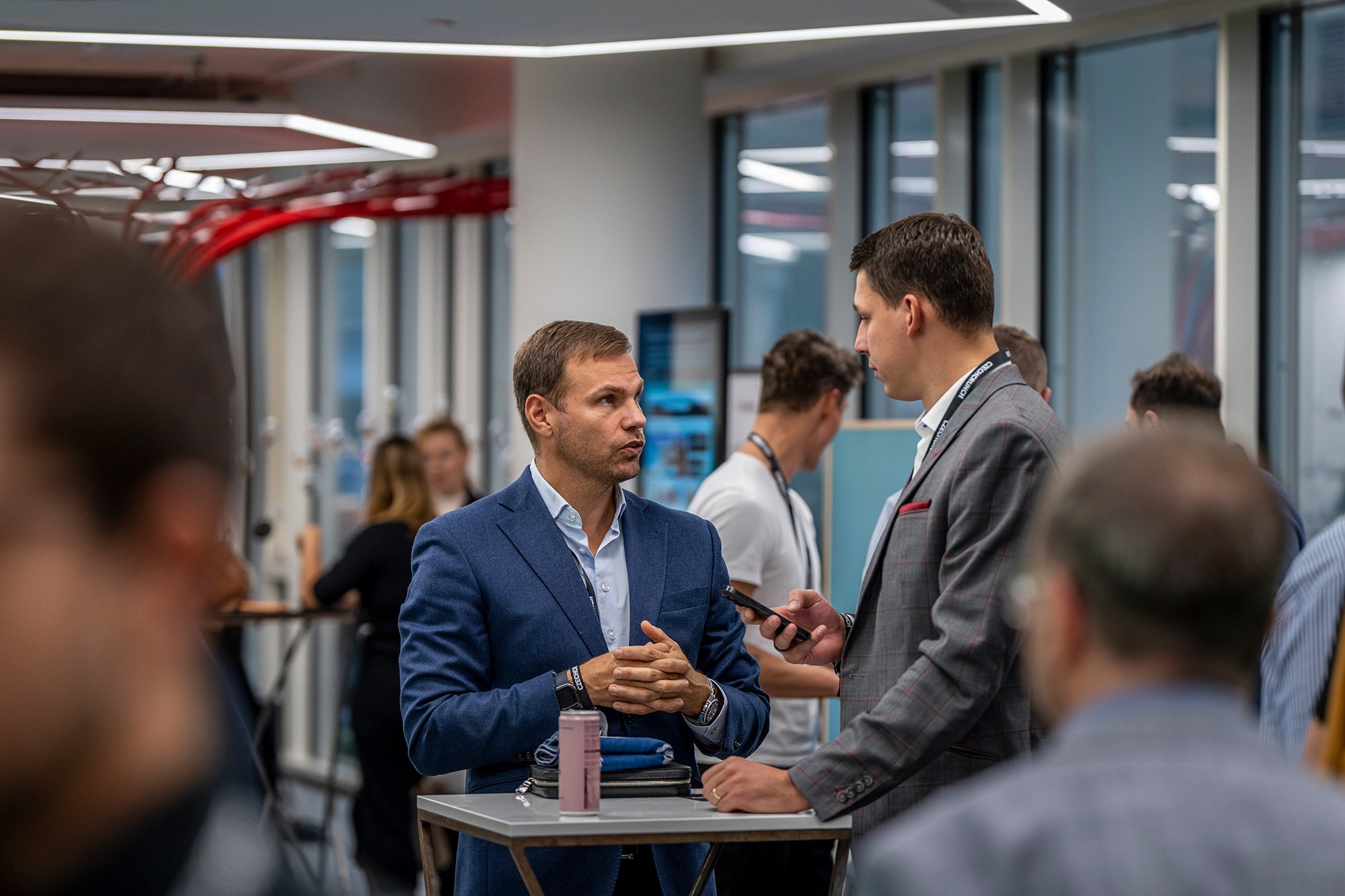Business professionals networking at Money Maker conference in Prague, candid conversation during a break between sessions.
