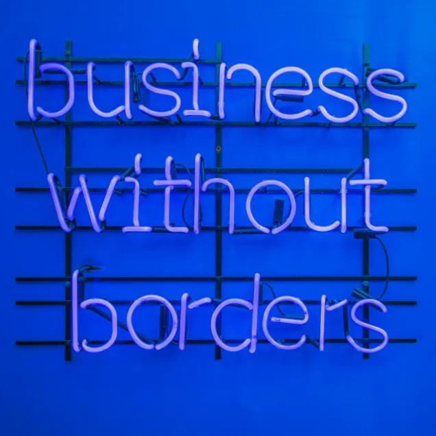Neon sign reading "business without borders" in purple against a vibrant blue background. 