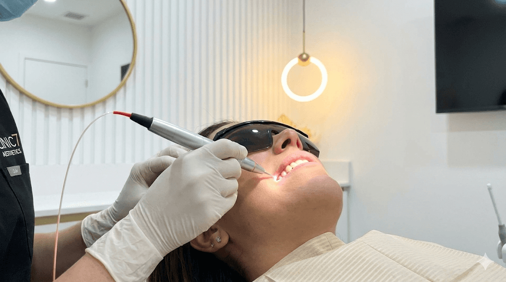 A specialized dental laser handpiece being used precisely along the gum line.