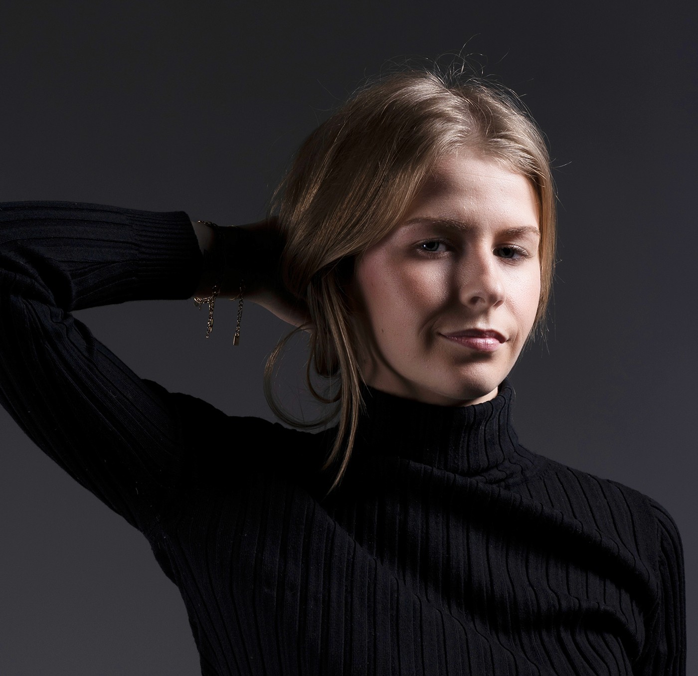 portrait femme studio fond noir  se tenant les cheveux